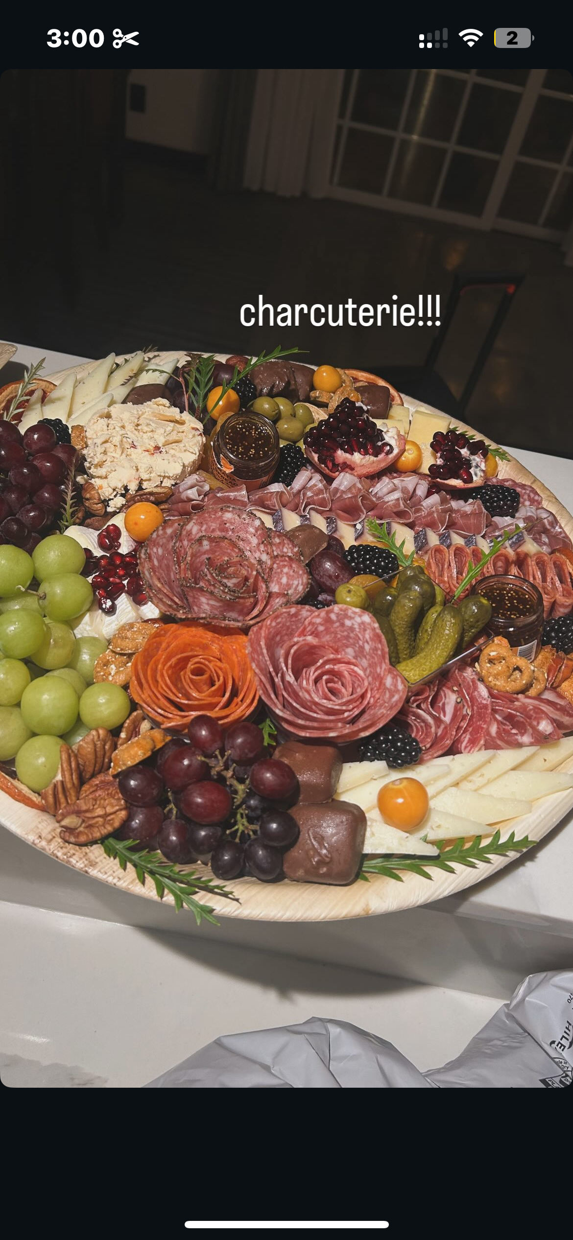 Charcuterie platter with assorted meats, cheeses, grapes, blackberries, pomegranate, pickles, nuts, and small jars of jelly or jam.