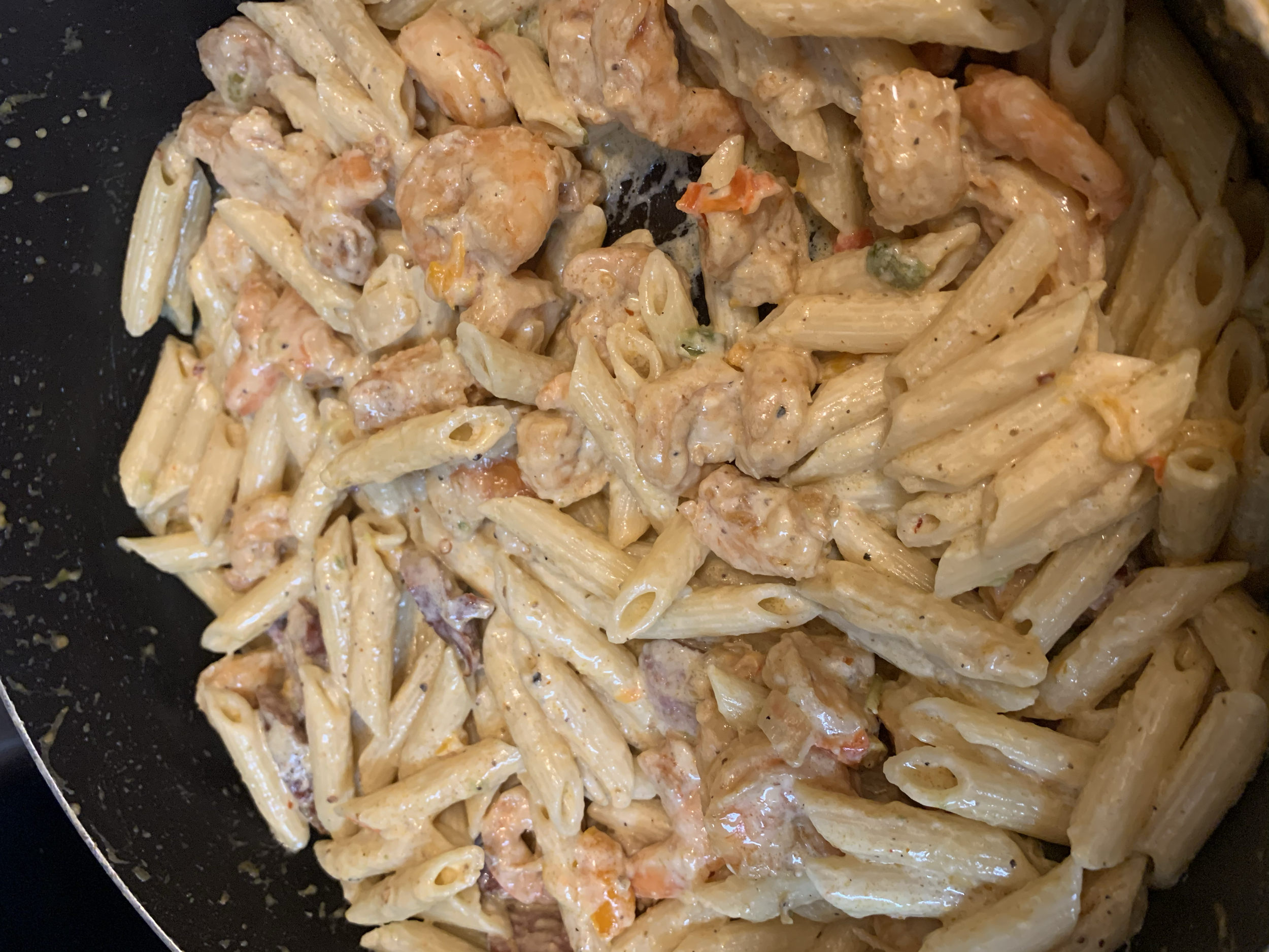 Creamy penne pasta with chunks of chicken, diced tomatoes, and green herbs.