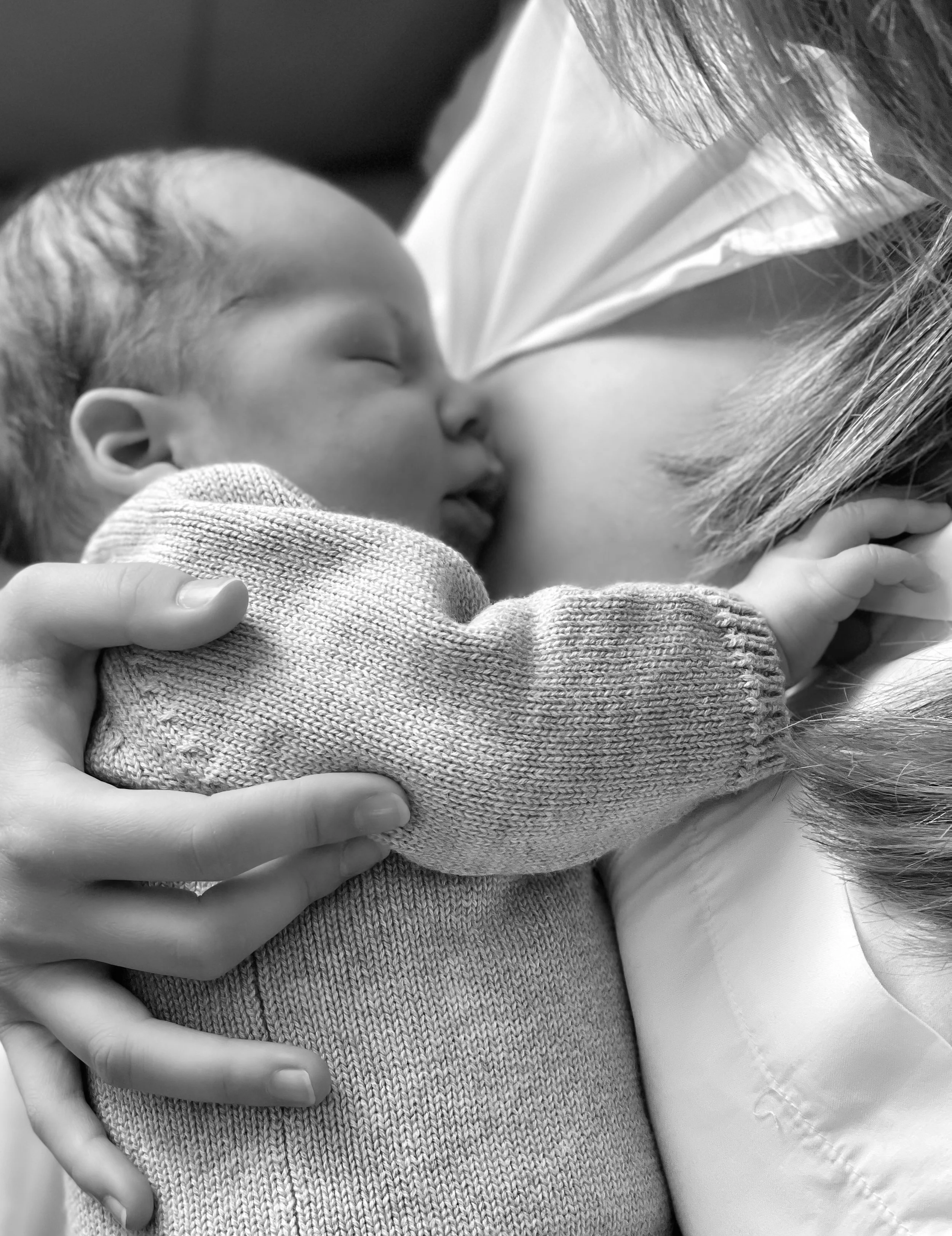 Un bébé en train de dormir tout en étant blotti contre sa mère, qui l'allaite.