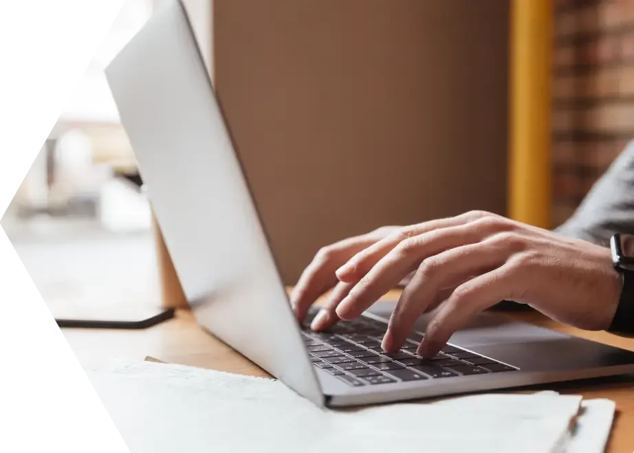 Person typing on a laptop at a wooden desk.