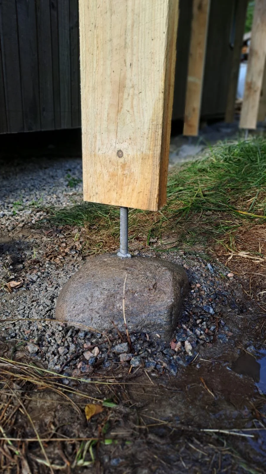 Een houten paal bevestigd op een rots met een verlichte steelbeschermer, fundering voor een houtopslag.