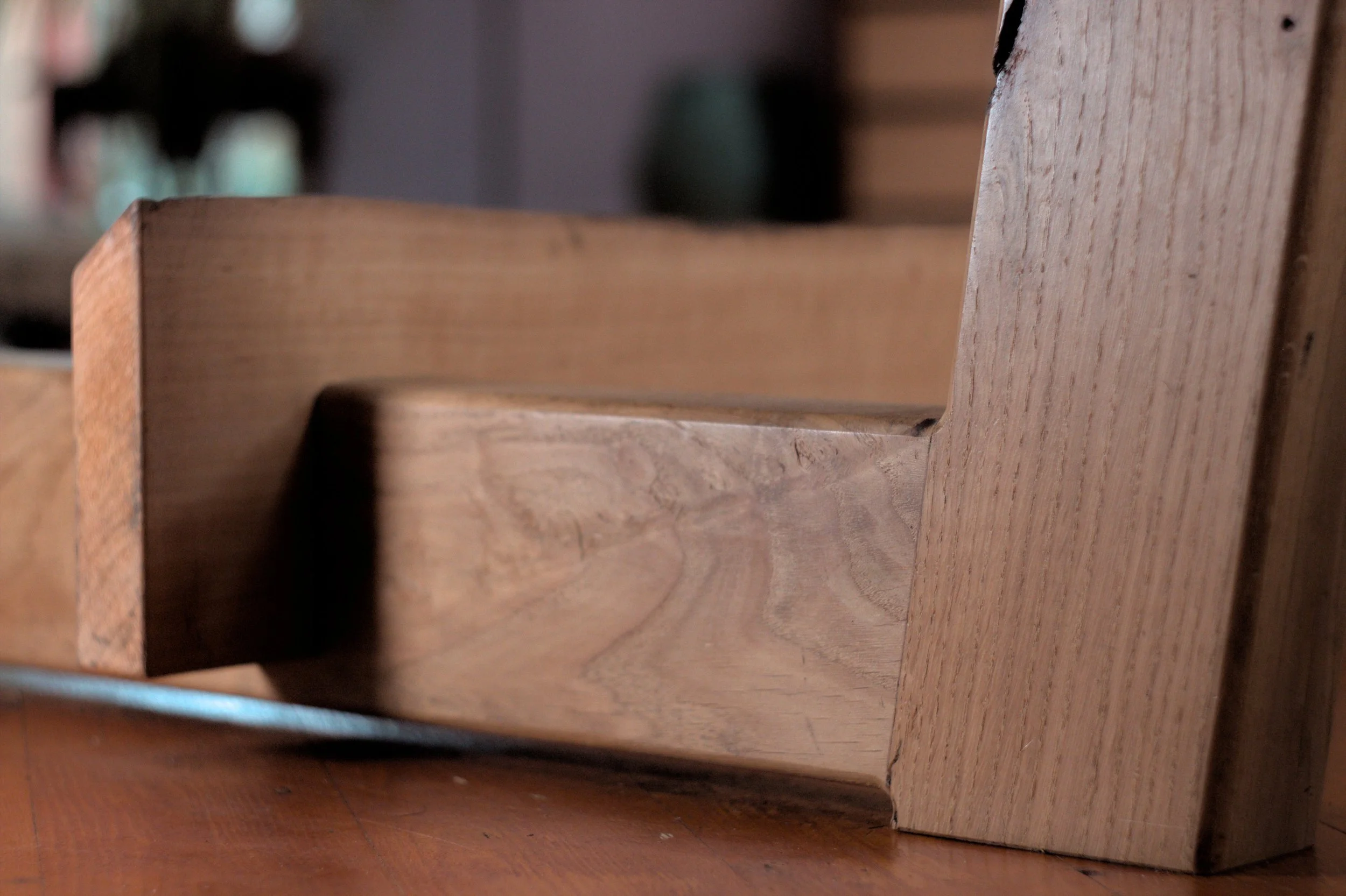 Close-up van een houten meubelstuk met een rechte kant en een afgeronde rand, gemaakt van lichtbruin hout met zichtbare nerf.