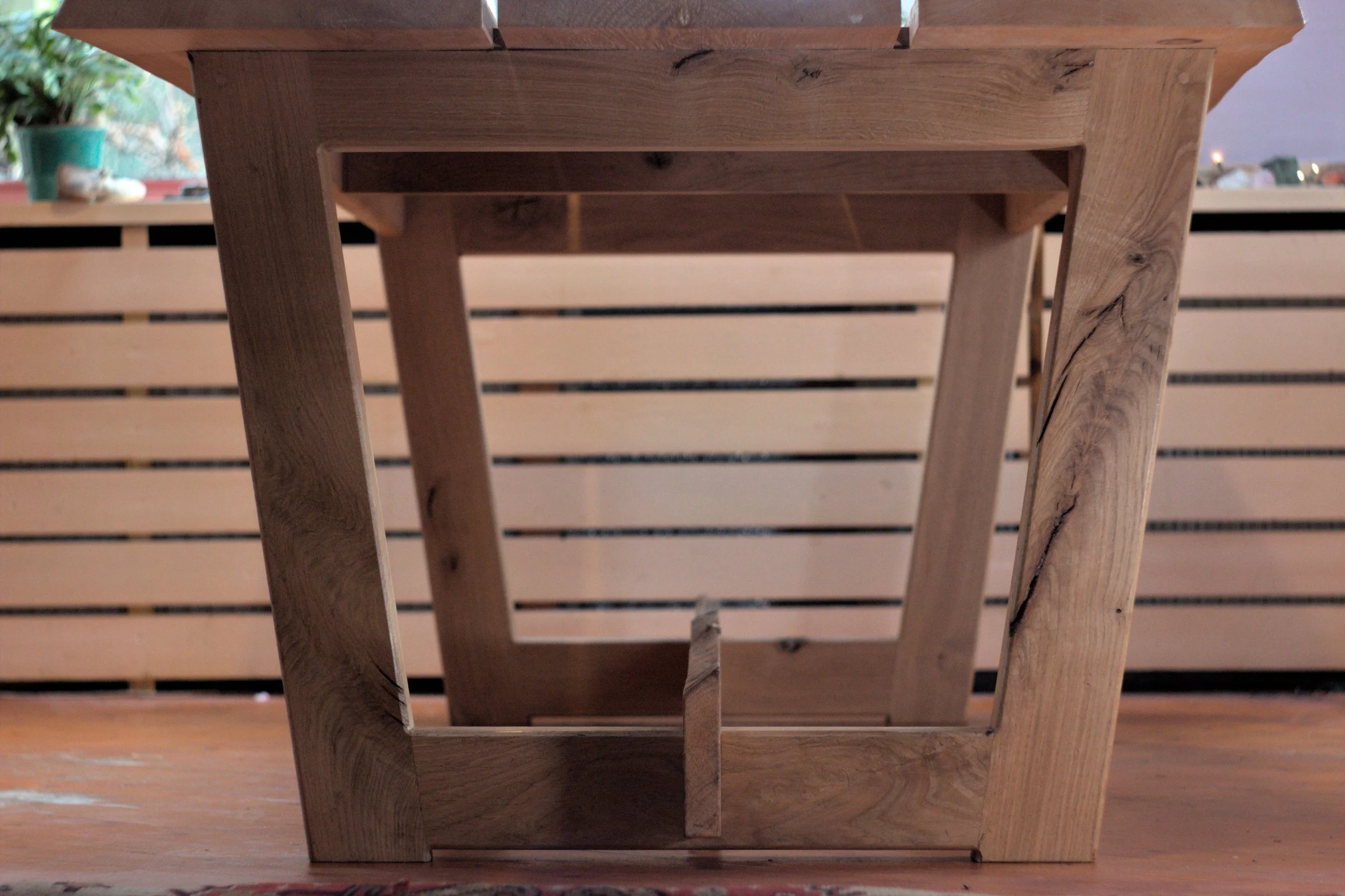 Een tafel gemaakt van eikenhout en iepenhout, met een open, vierkante structuur en een natuurlijke houtafwerking.