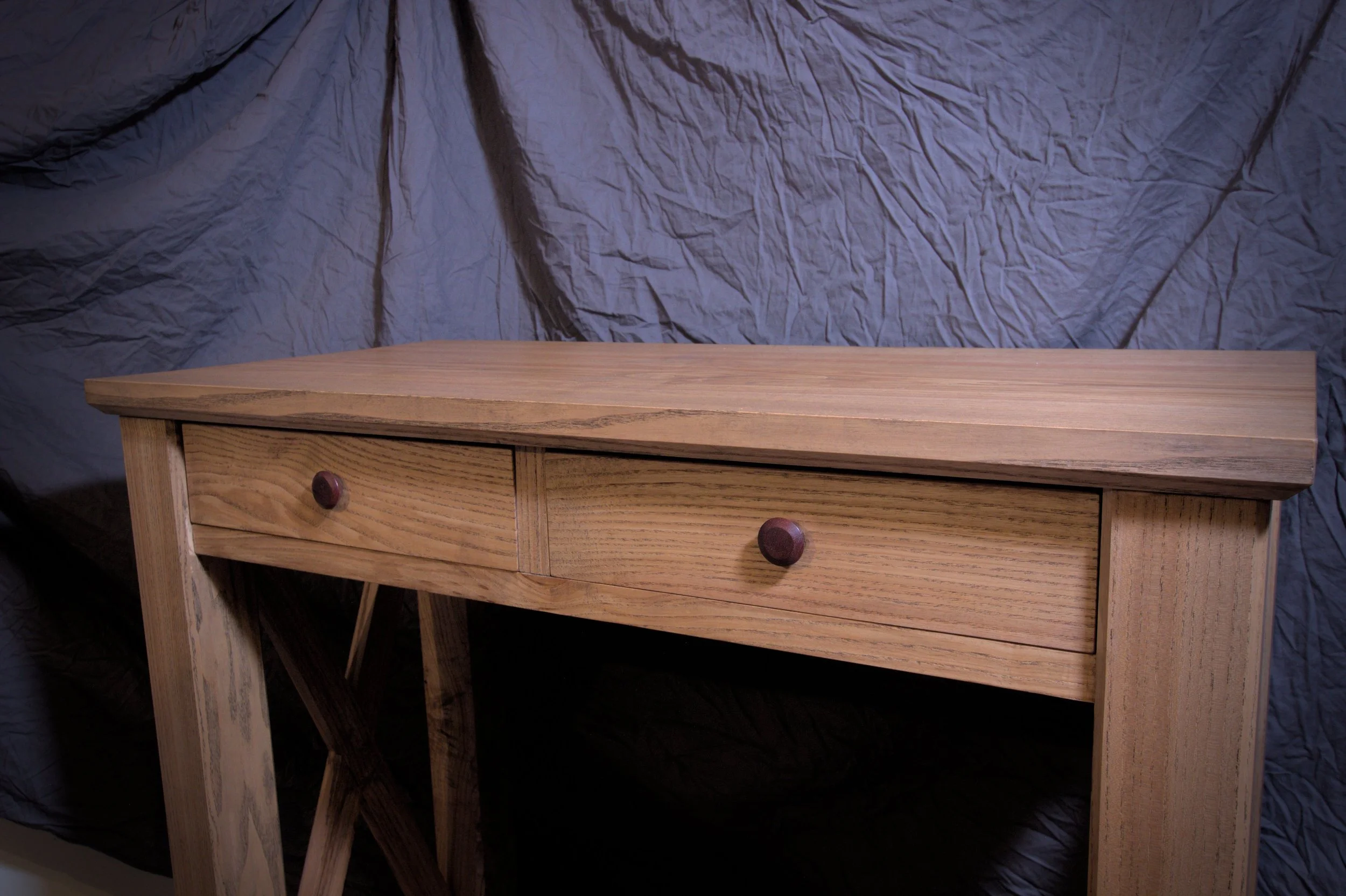 Een houten tafel met twee laden, geplaatst voor een donker, bedrukte achtergrond.