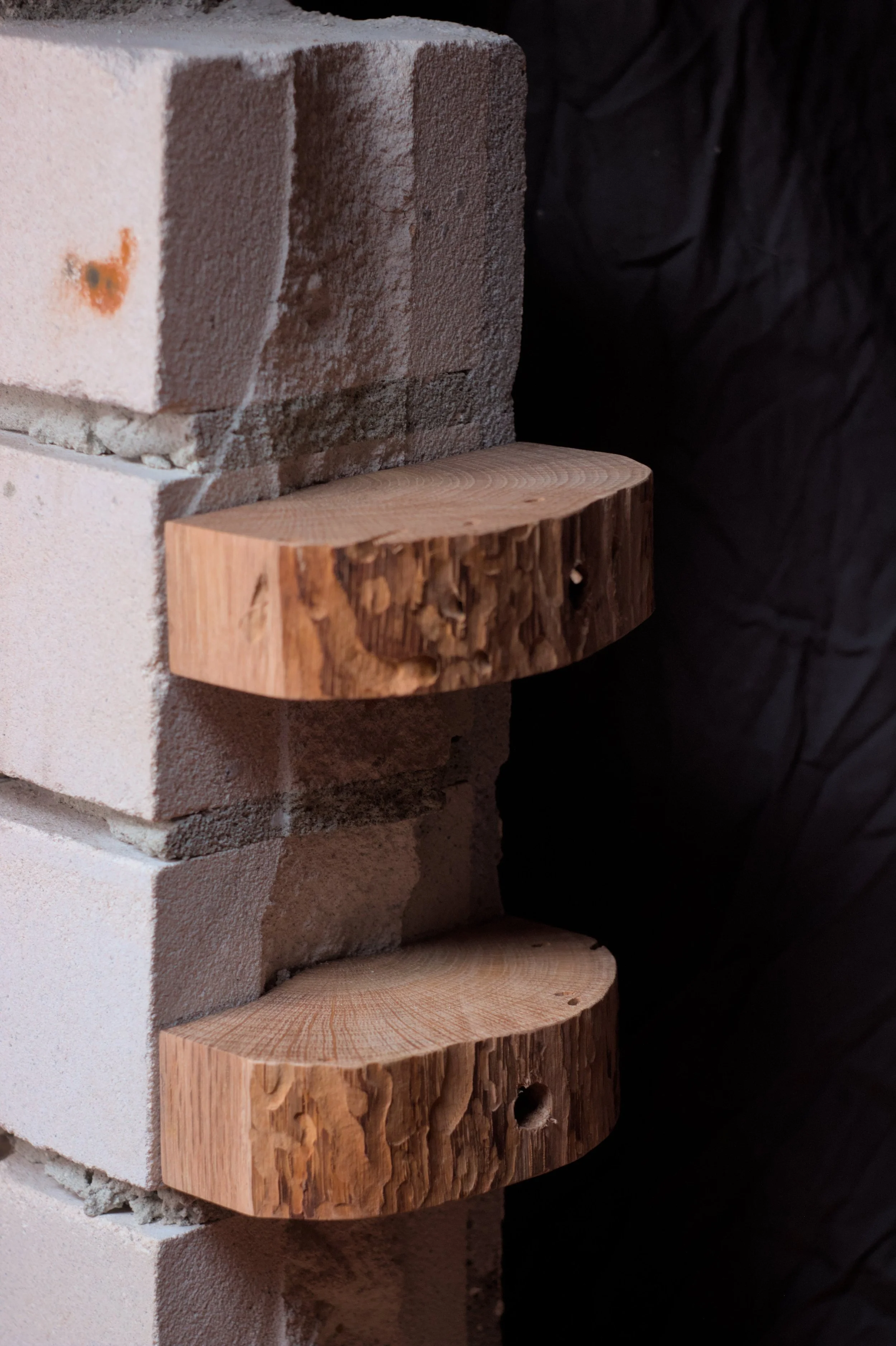 Brik en houten blokken gestapeld, met zwart doek op de achtergrond.