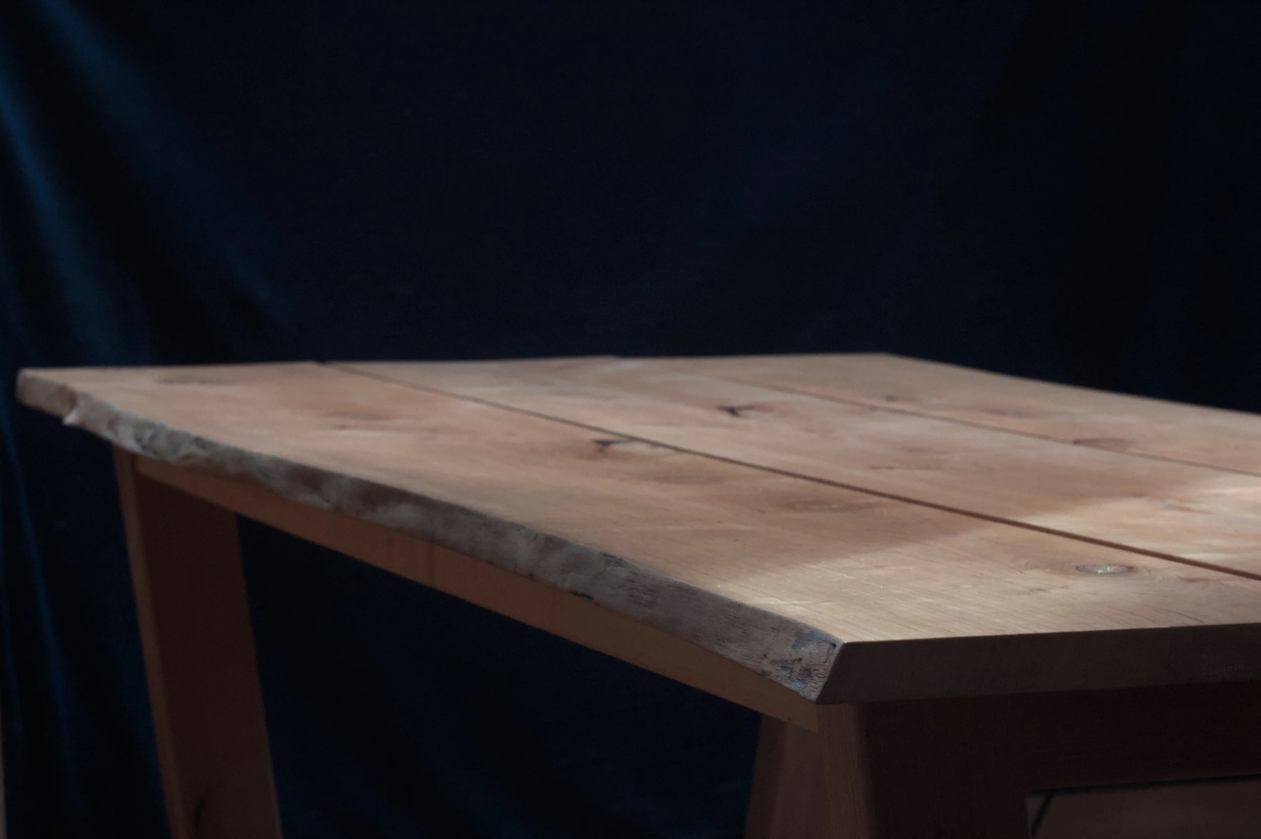Houten tafel met natuurlijke rand en donkerneutrale achtergrond.
