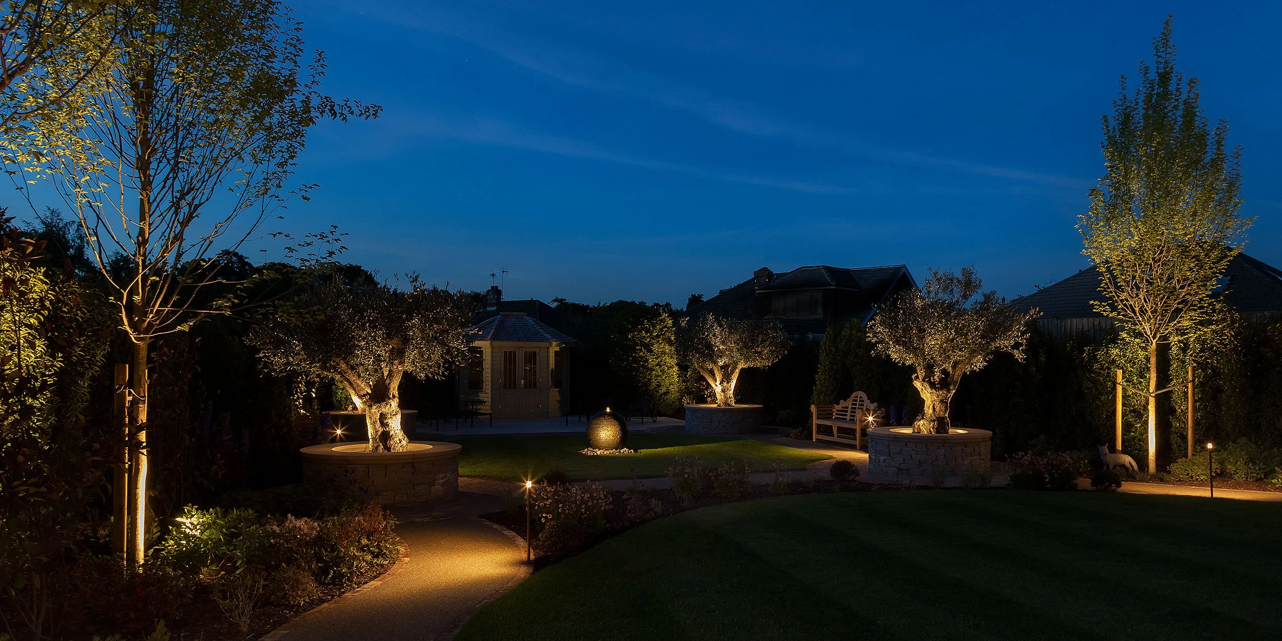 Landscape lighting illuminating planting, hardscape and outdoor zones after dark.