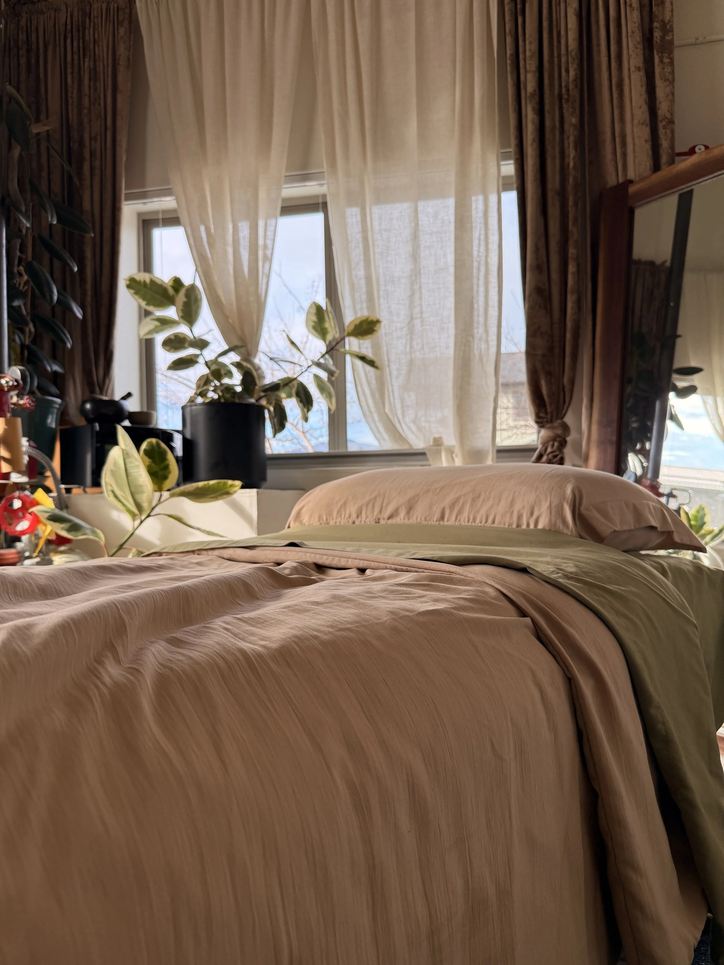 A warm and inviting therapy bed for massage therapy, lymphatic drianage massages, surrounded by green plants and warm morning light that feels soft and welcoming 