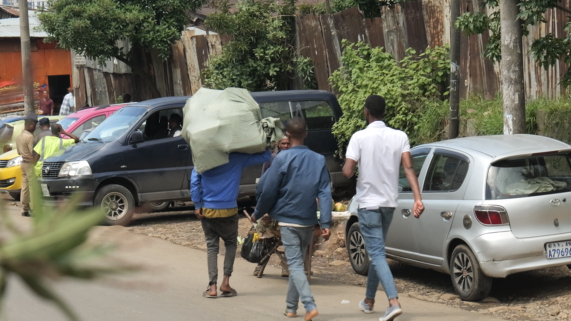 Ethiopian guys walking outside on the streets of Addis Ababa carrying goods on a nice day.
