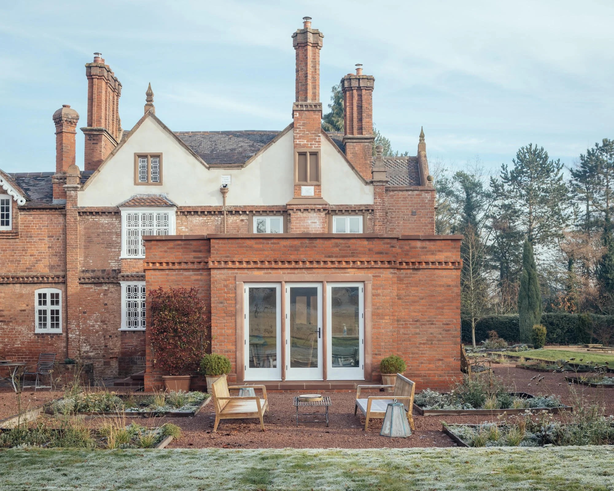 Ornate architectural features of the manor echoed by garden ornaments and structured beds