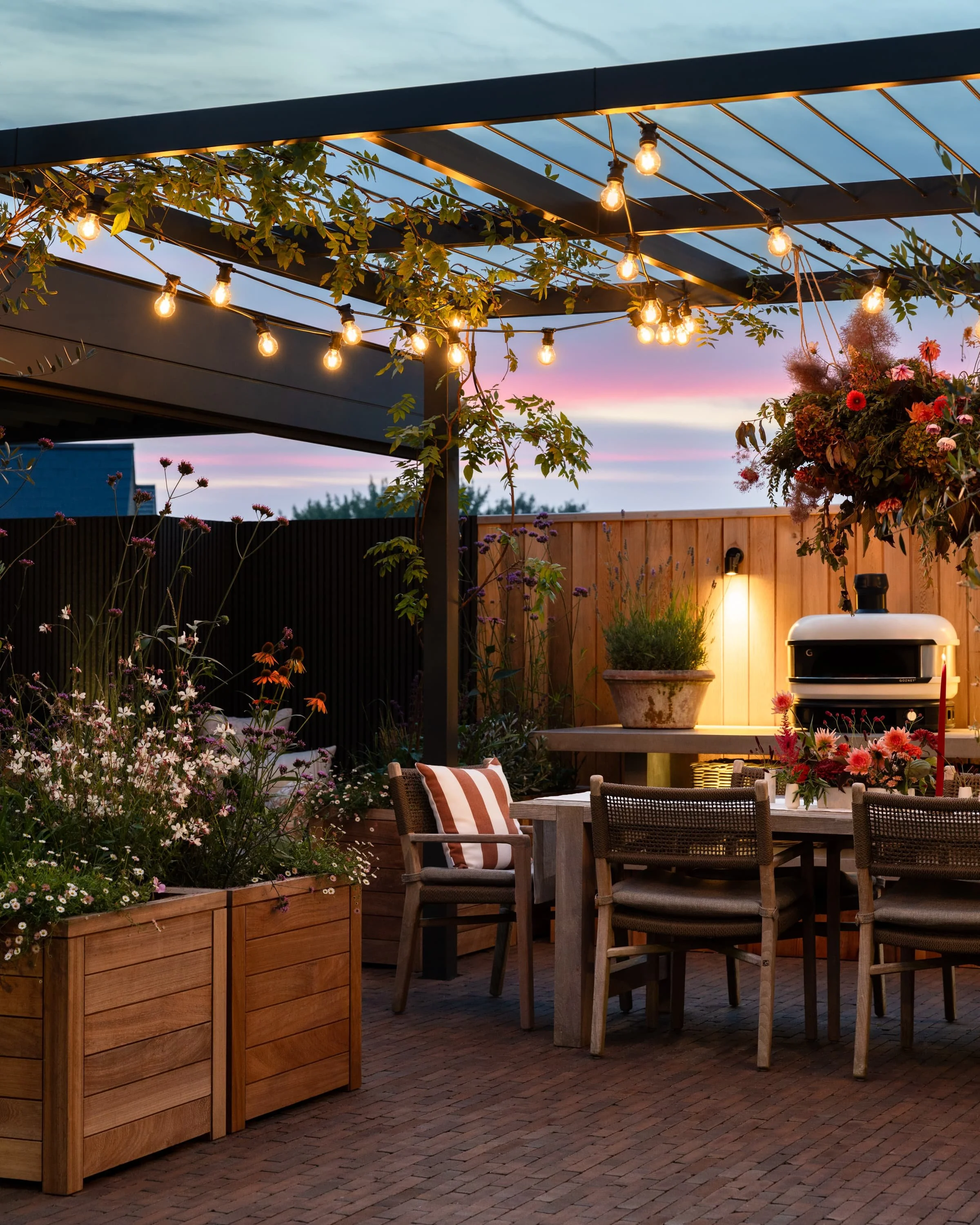 Soft ambient lighting highlighting the pergola, fireplace, and outdoor seating areas