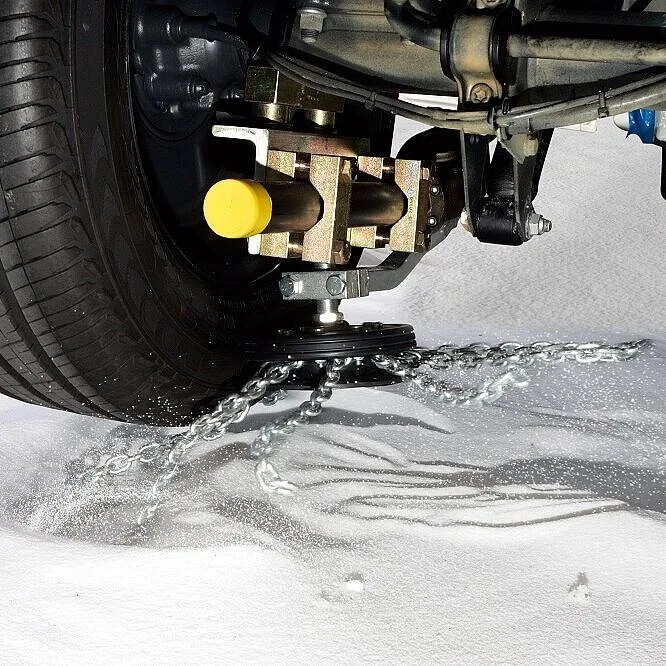 A close-up of a vehicle's undercarriage with water spraying from a hose, indicating a cleaning process, on a light-colored surface.