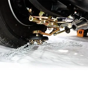 Close-up of a snowmobile's undercarriage near the ground with snow and ice.
