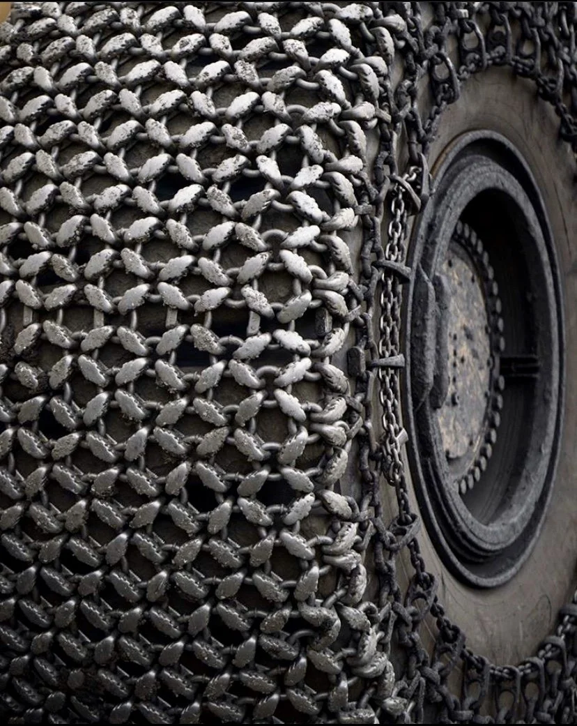 Close-up of metal chains wrapped around a large tire.