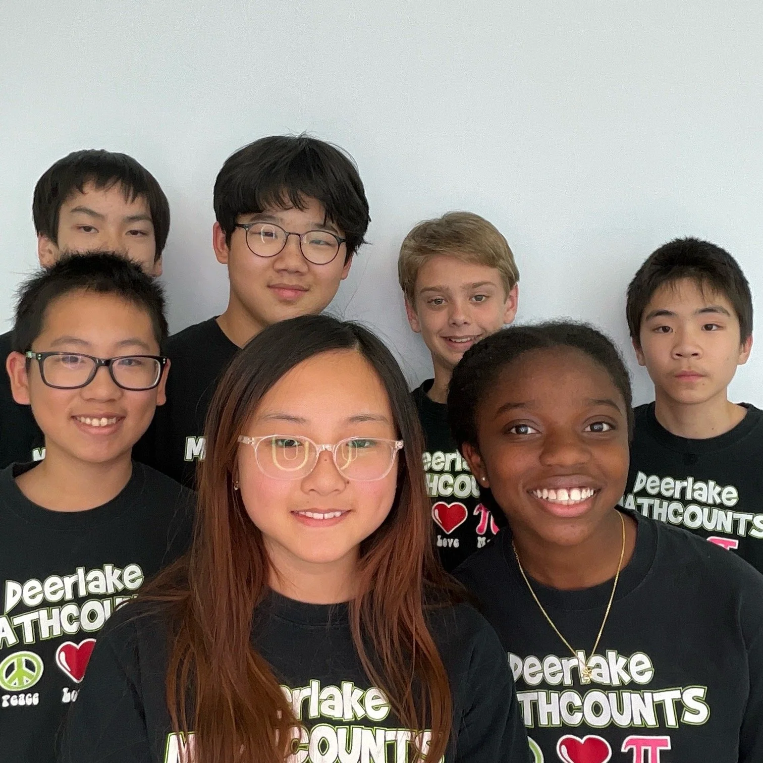 Group of diverse students wearing Deerlake Mathcounts shirts, smiling for a photo.