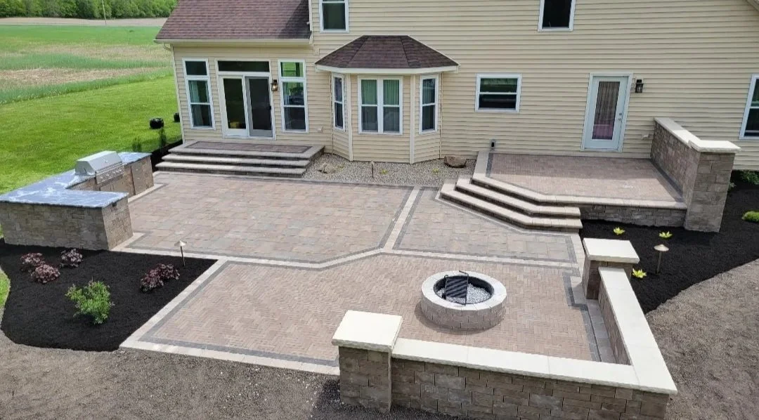 Paver patio with grill island, fire pit, decorative seat wall and two raised areas