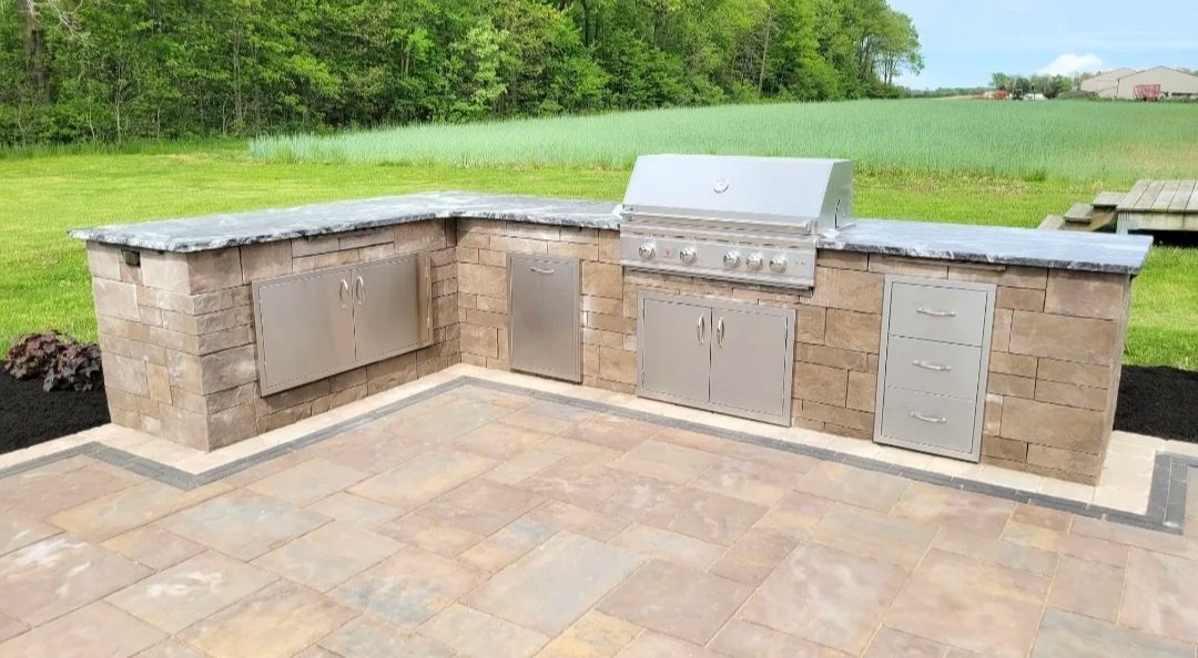 Outdoor hardscape grill island with grill and accessory cabinets