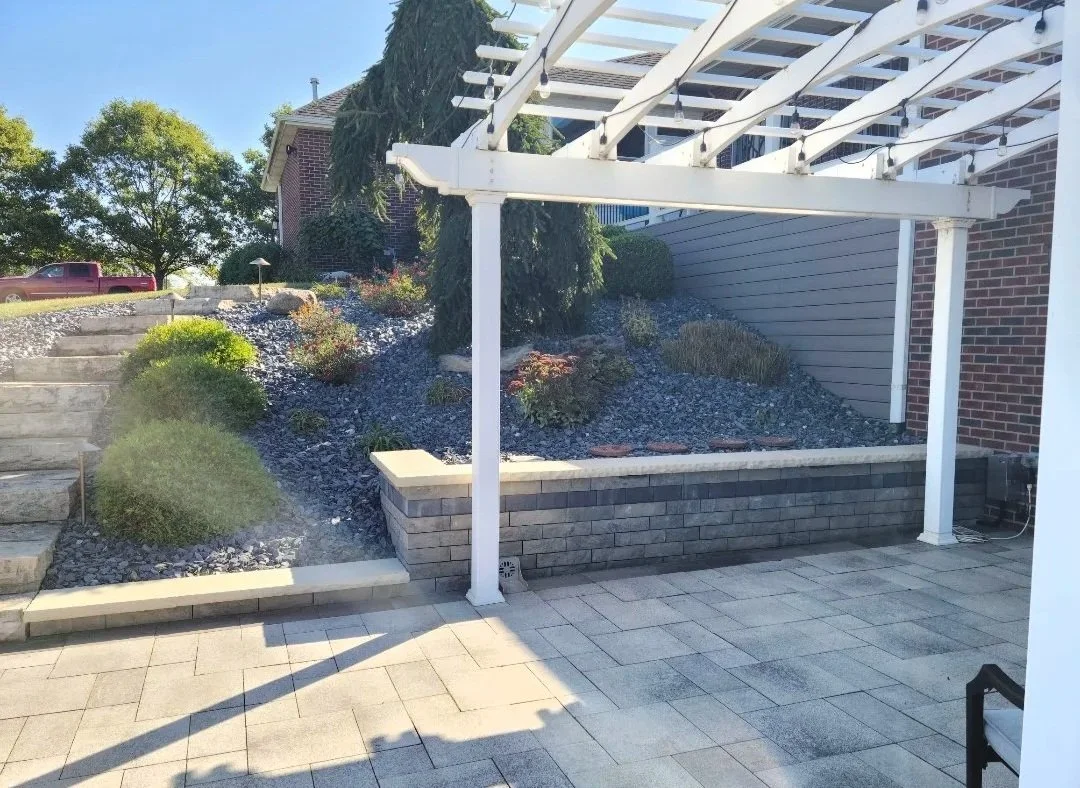 Paver patio with a pergola and a retaining wall