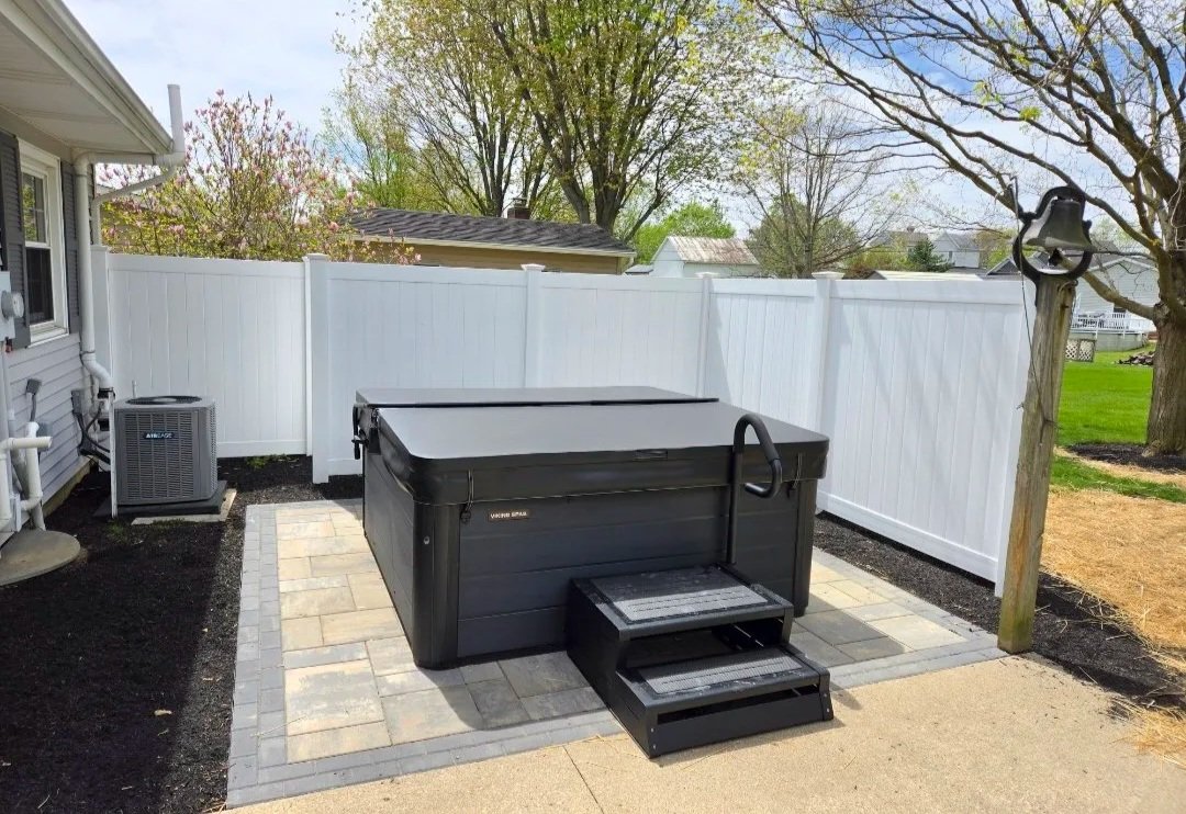 Paver patio with a hot tub and a white vinyl privacy fence