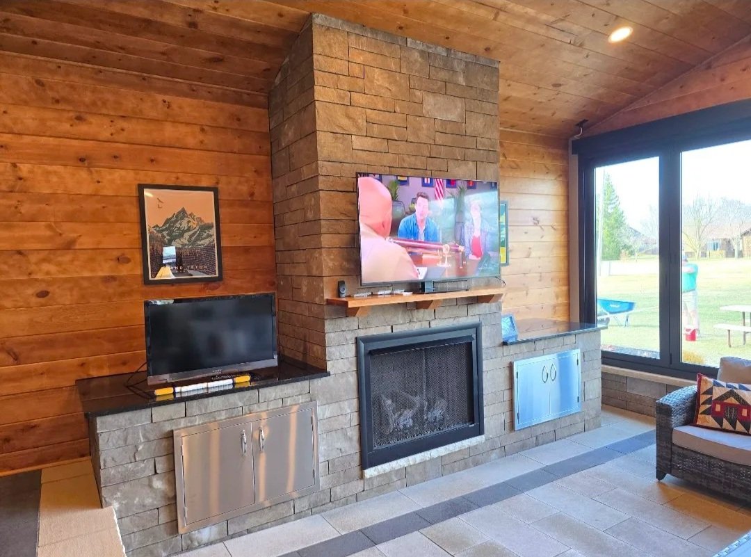 outdoor living space with pavers an outdoor counter top, fireplace and bi-fold windows with screens