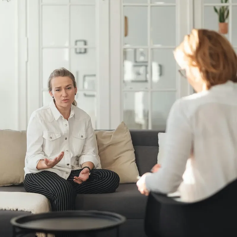 woman sitting on sofa talking to therapist