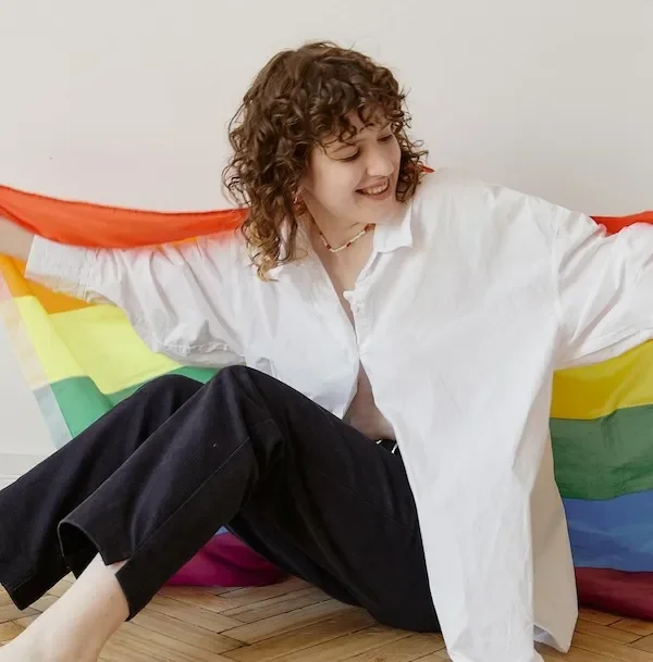 woman sitting holding out lgbtq flag