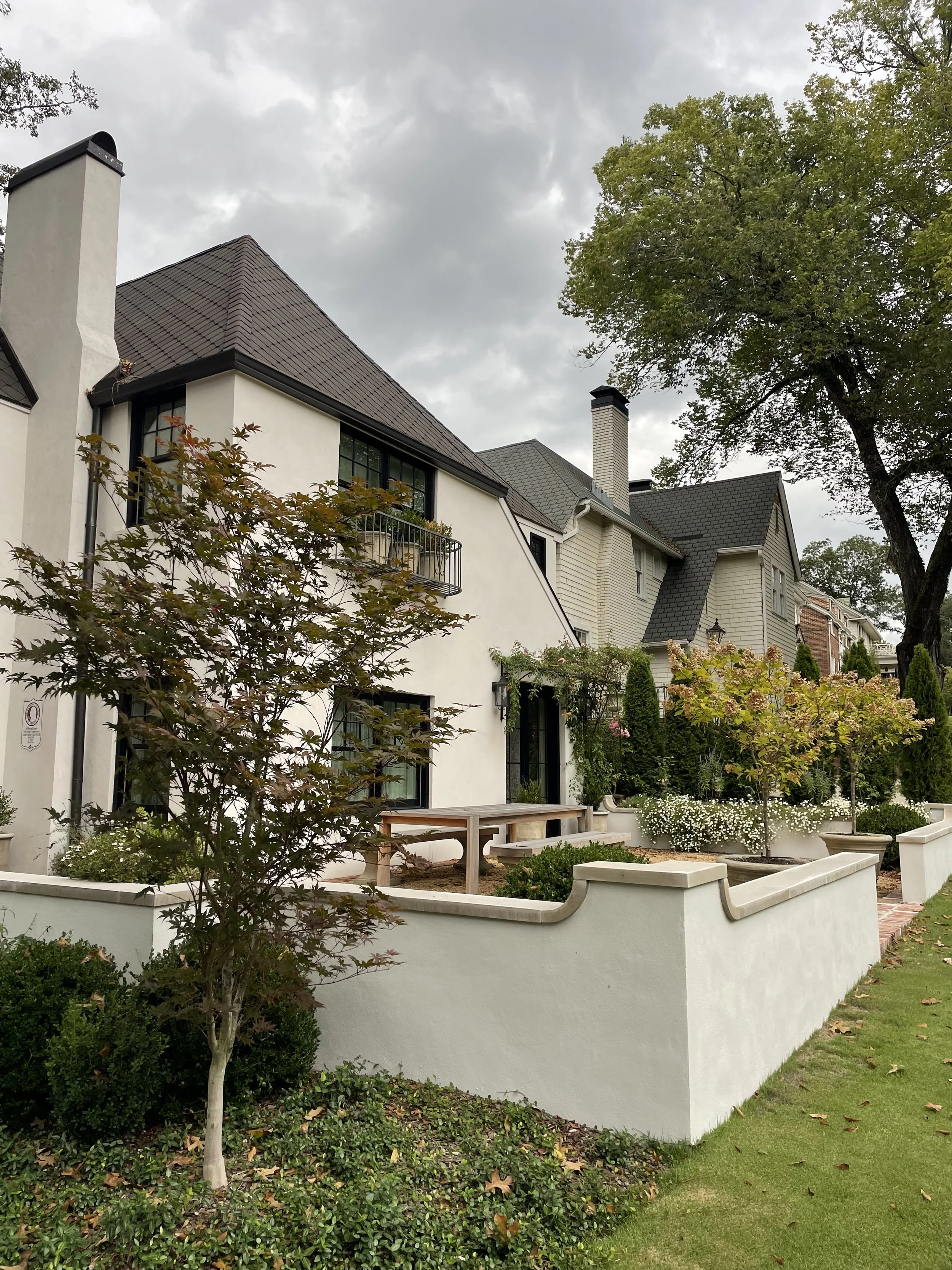 A residential house with a garden and trees on a cloudy day.