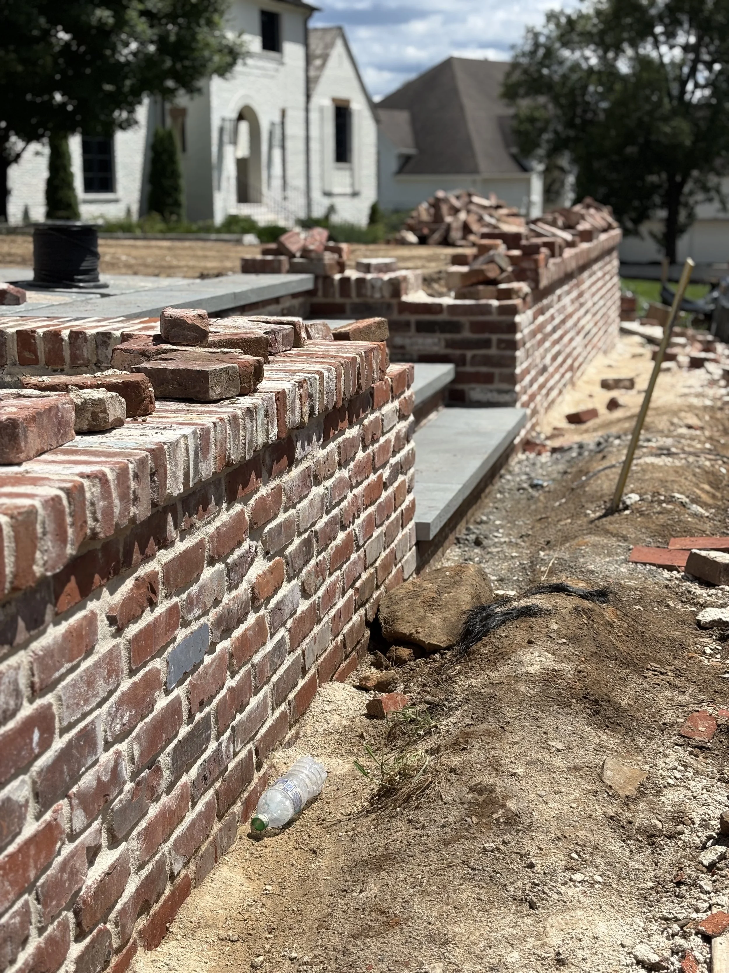 Under construction brick wall with partially built steps seen in a residential area built by Iron City Retaining Walls, a retaining wall builder in Central Alabama.