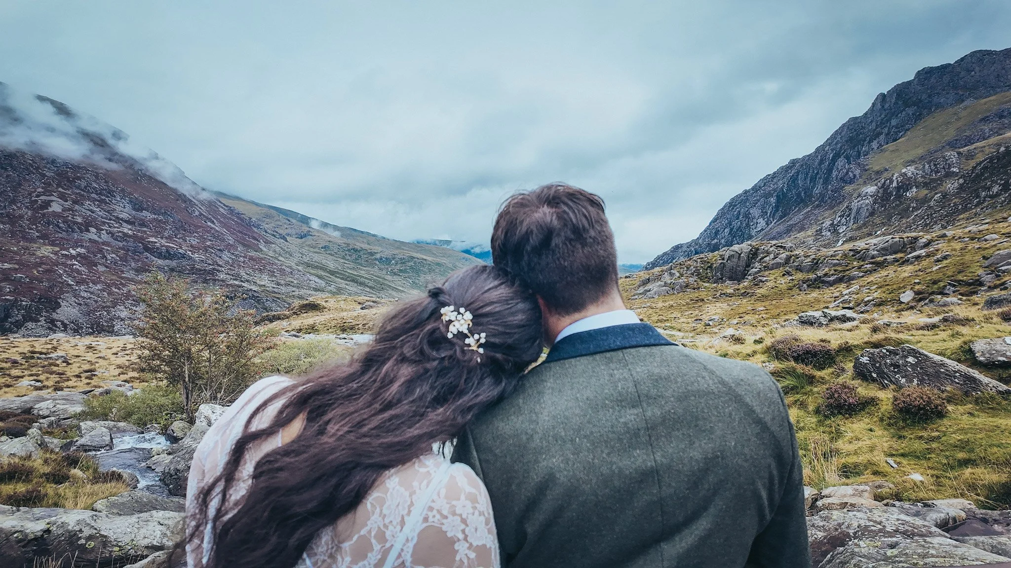 A couple seen from behind, looking out over a mountain valley