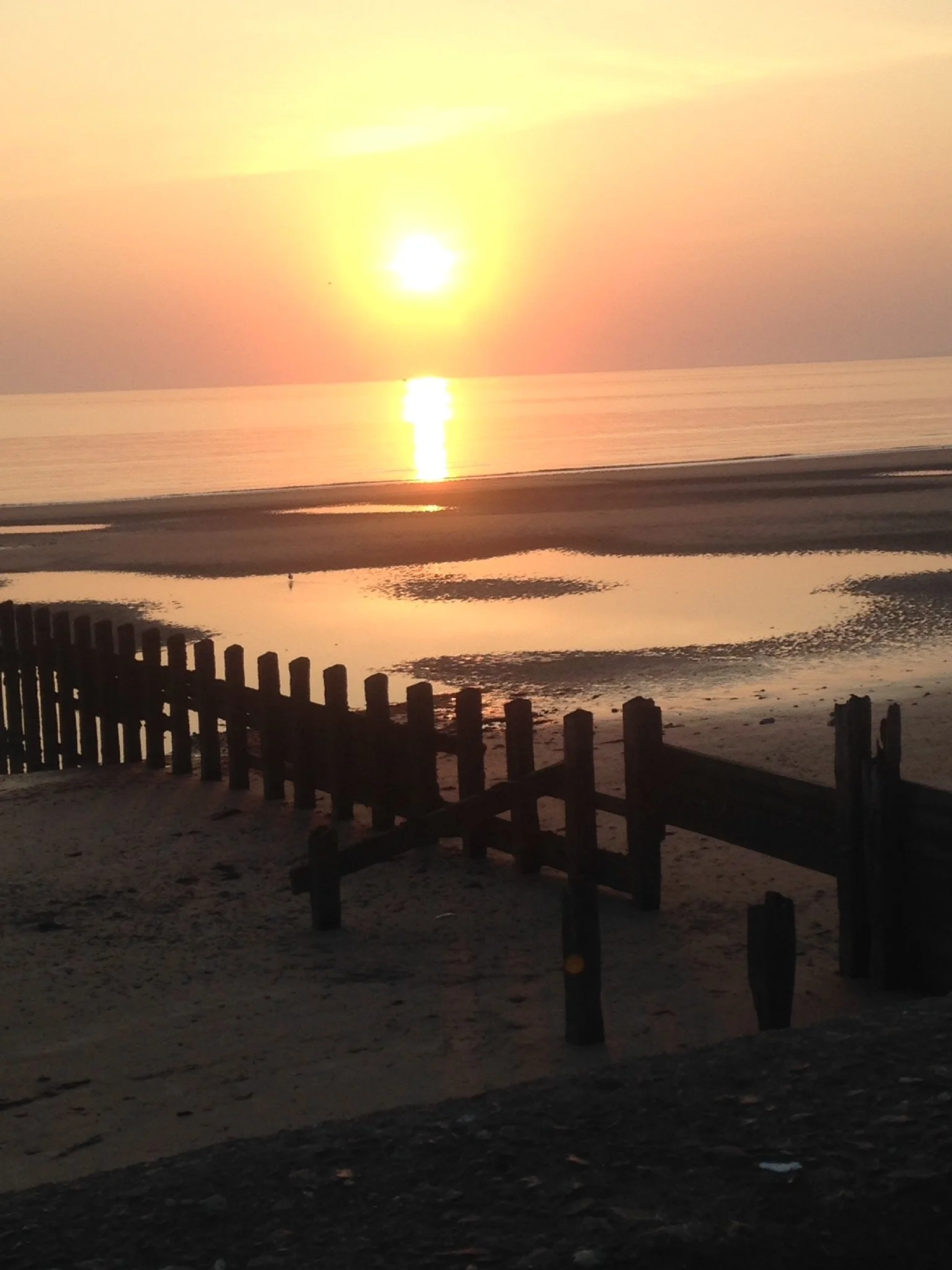 A golden sunset over the water at Barmouth, with the sky streaked with cloud