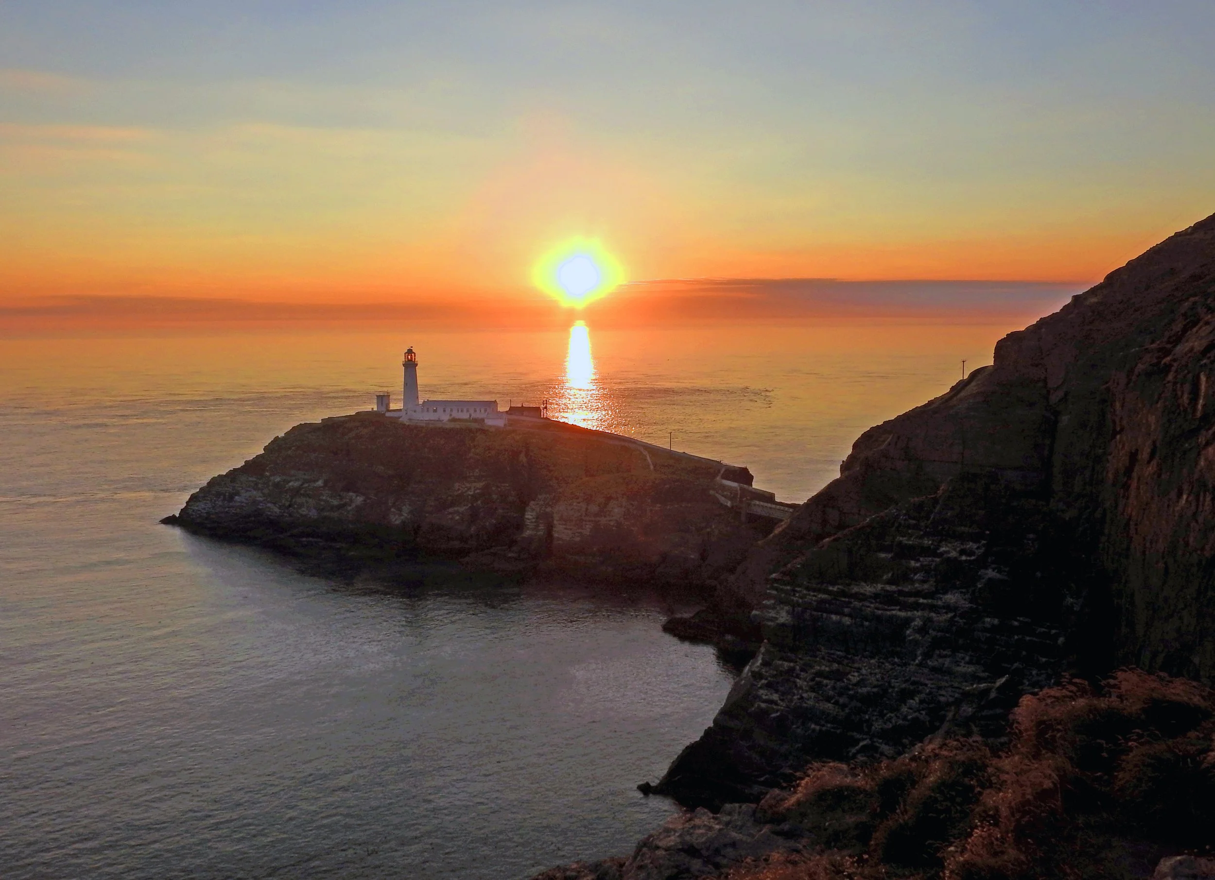 South Stack Lighthouse on its rocky island as the sun sets over the sea