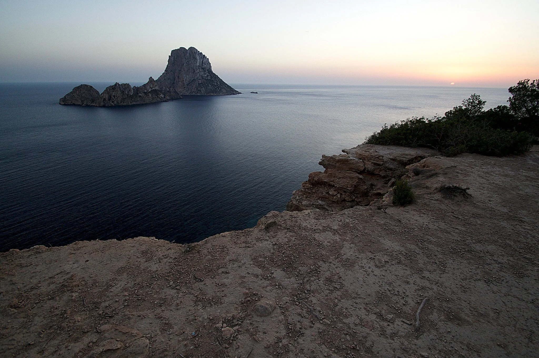 The rocky island of Es Vedrà rising from the sea off the coast of Ibiza, seen from the clifftop