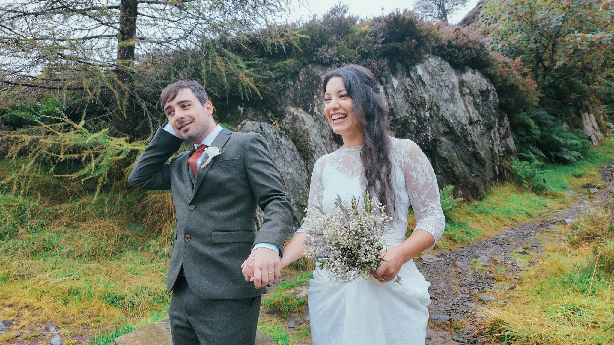 A couple laughing together on a path among rocks and ferns
