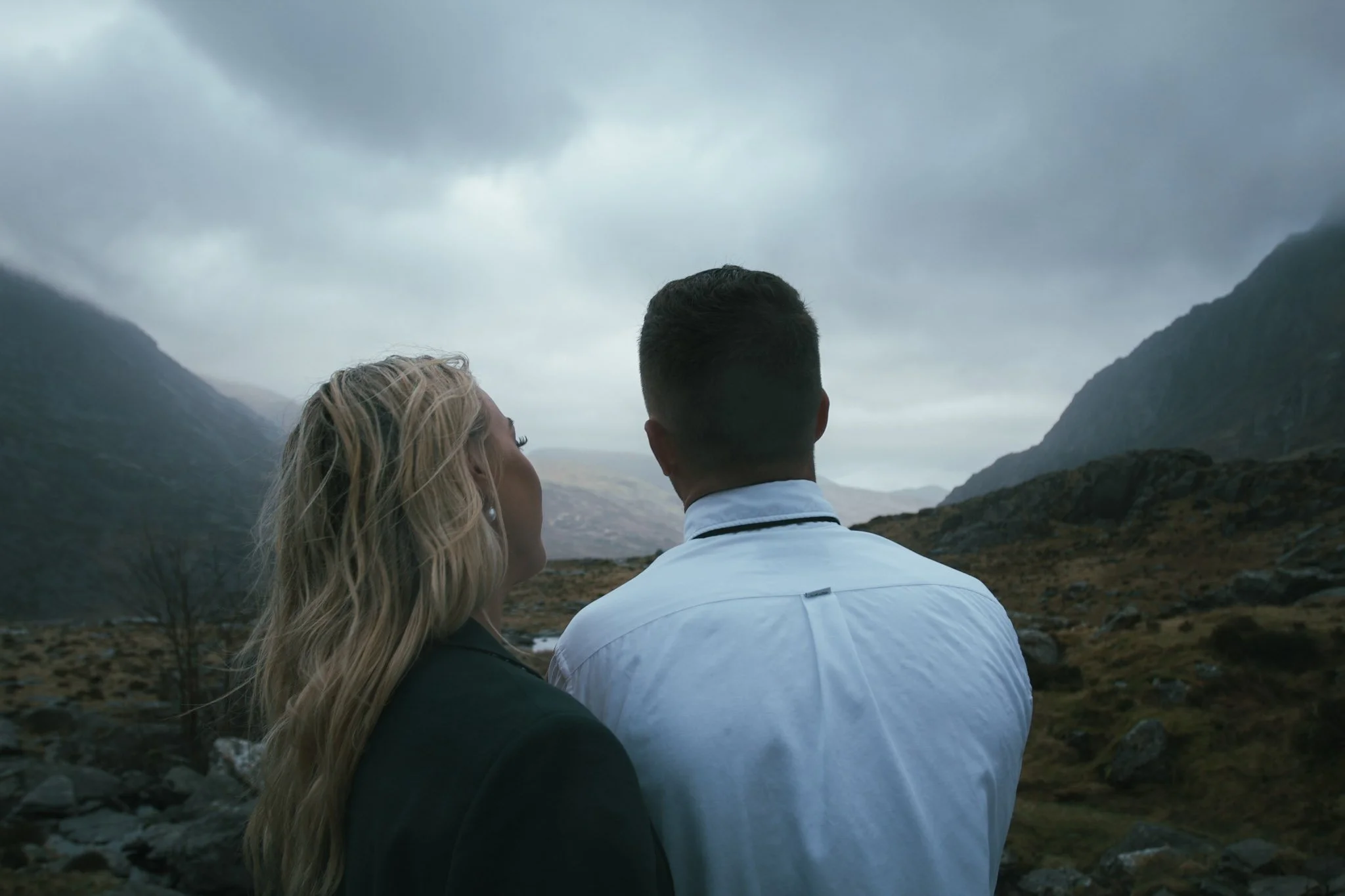 A couple seen from behind, gazing across a mountain valley