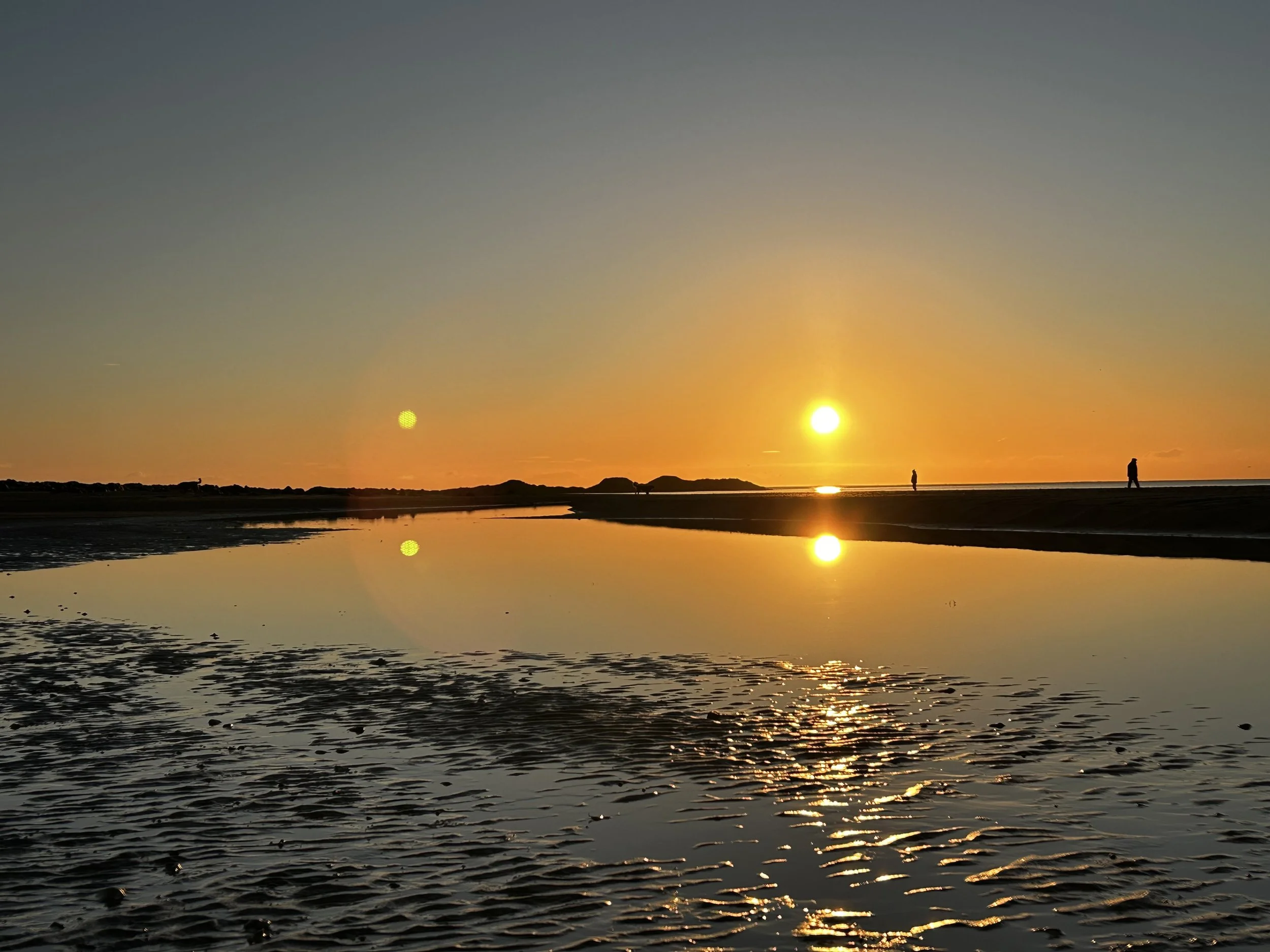 Sun setting over the wet sand at Rhosneigr on Anglesey