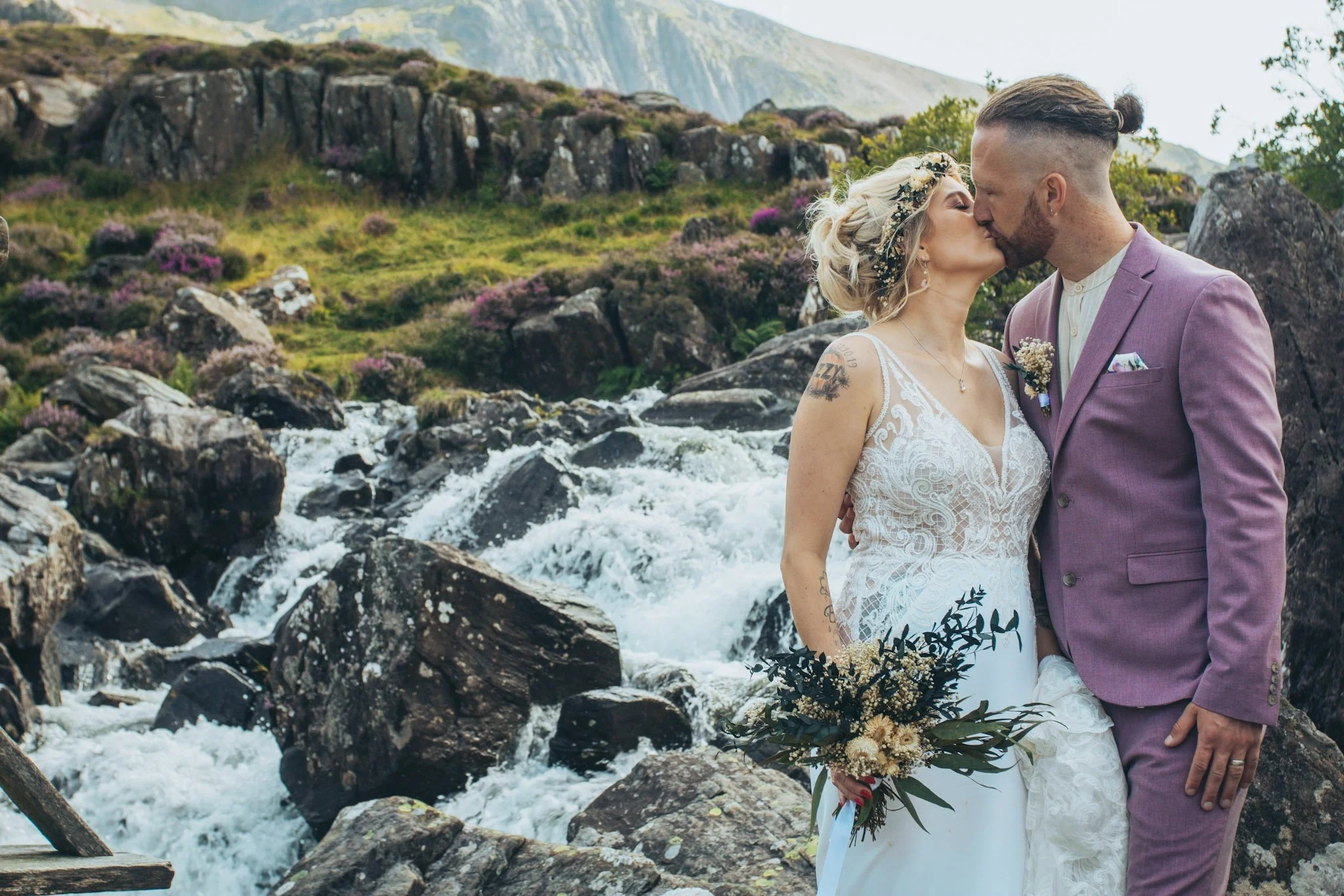 A couple kissing beside a mountain waterfall