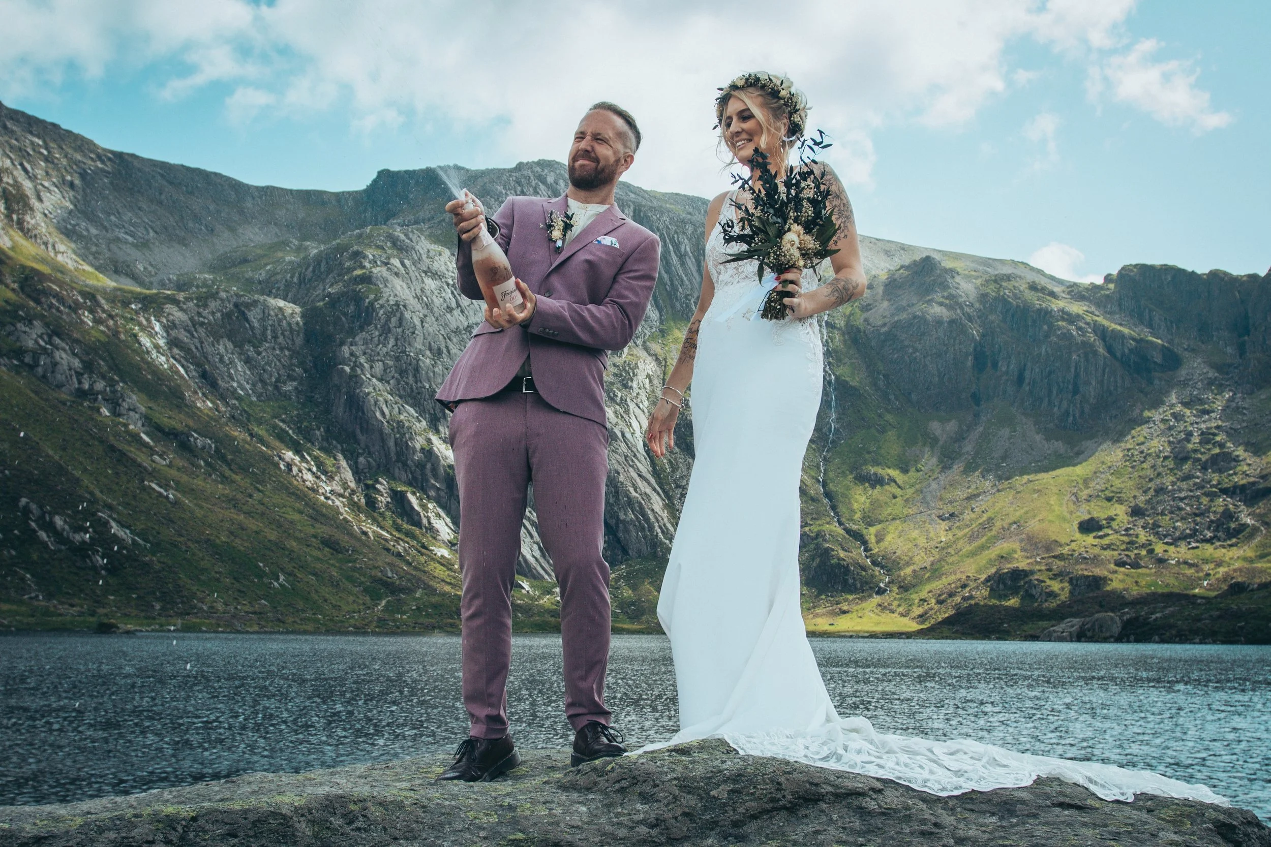 A couple celebrating with champagne beside a mountain lake