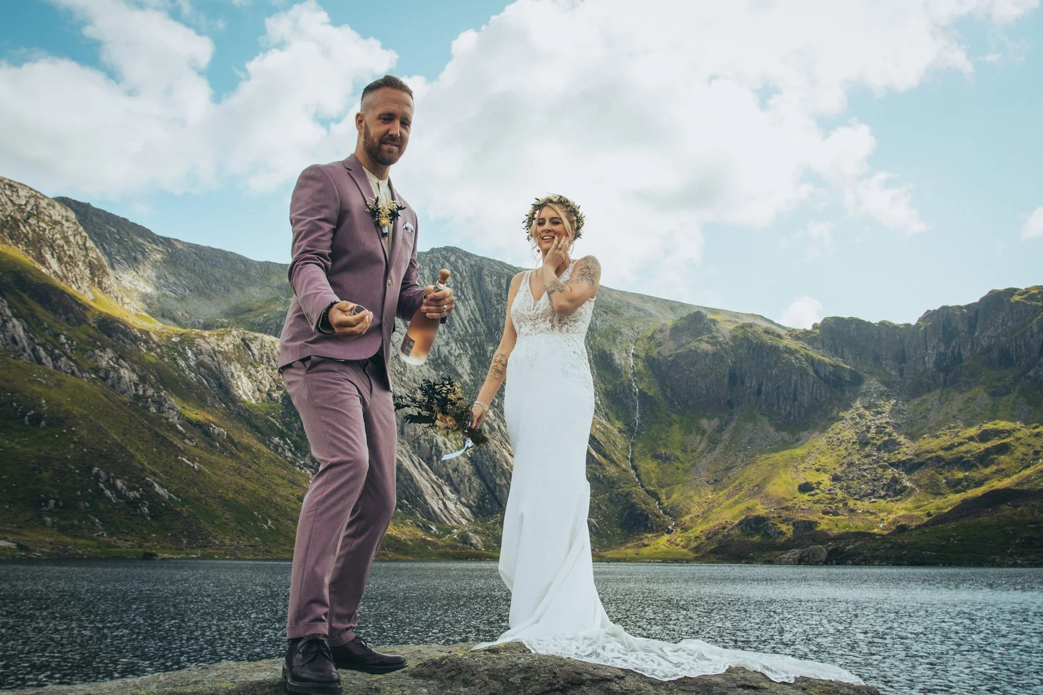 A couple celebrating with champagne beside a mountain lake