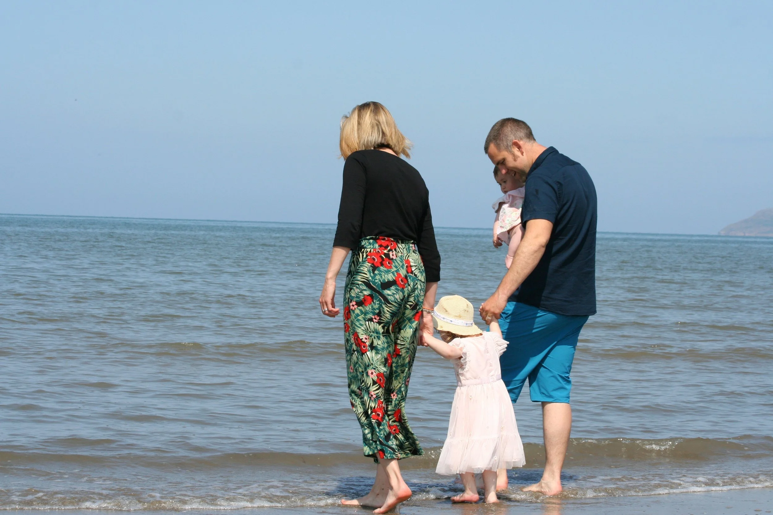 A couple paddling at the water's edge with a toddler