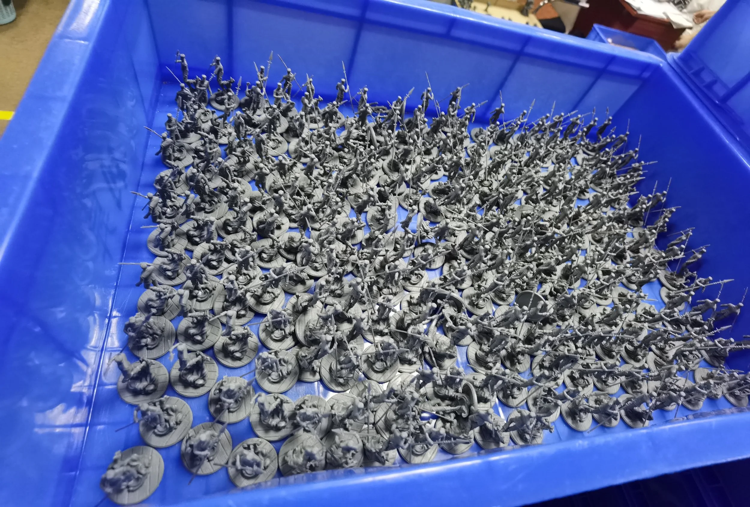 Unorganized collection of miniature toy soldiers in a blue plastic bin.