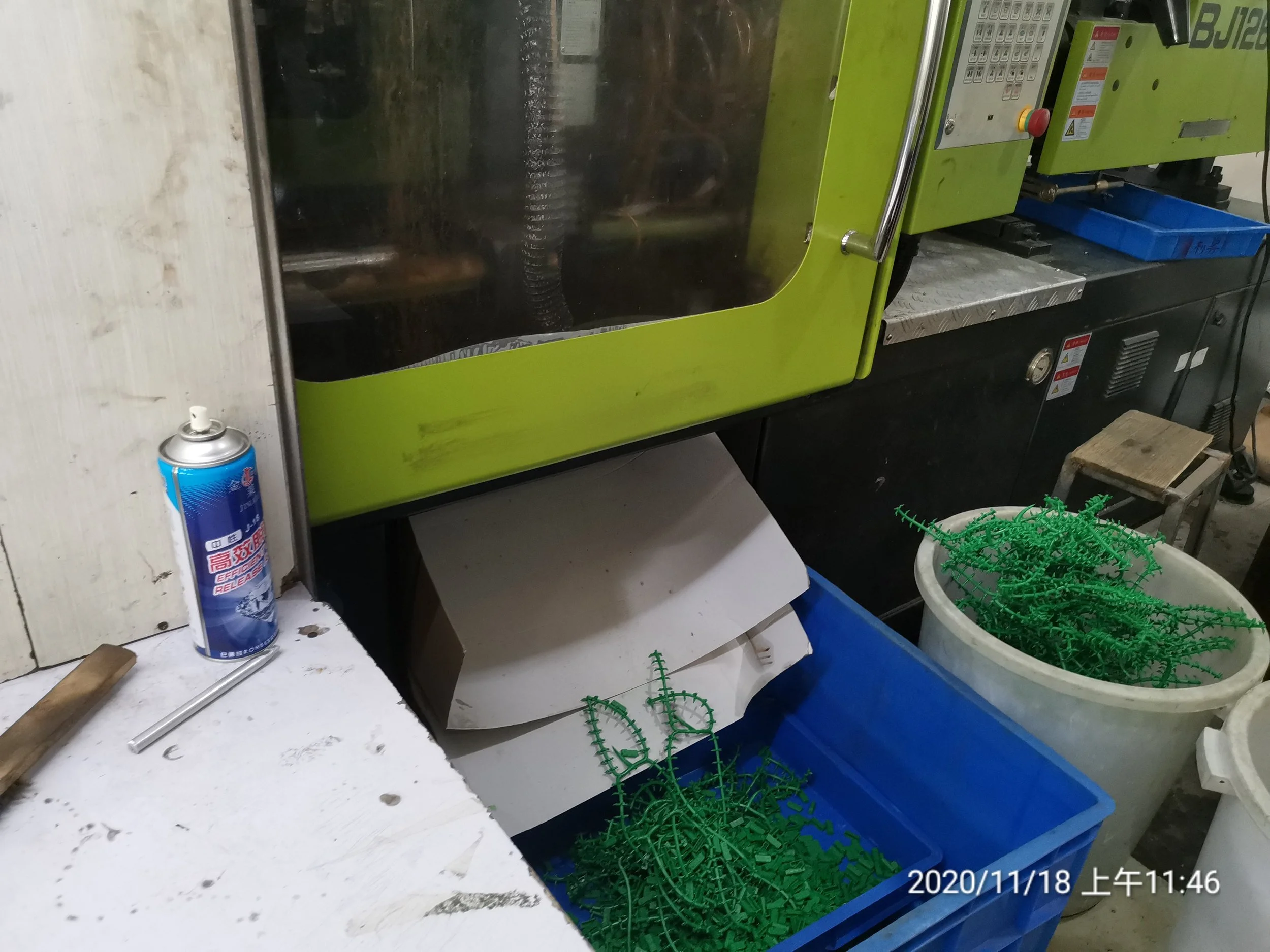 Workstation with green plastic components, a can of compressed air, and a machine in a workshop setting.