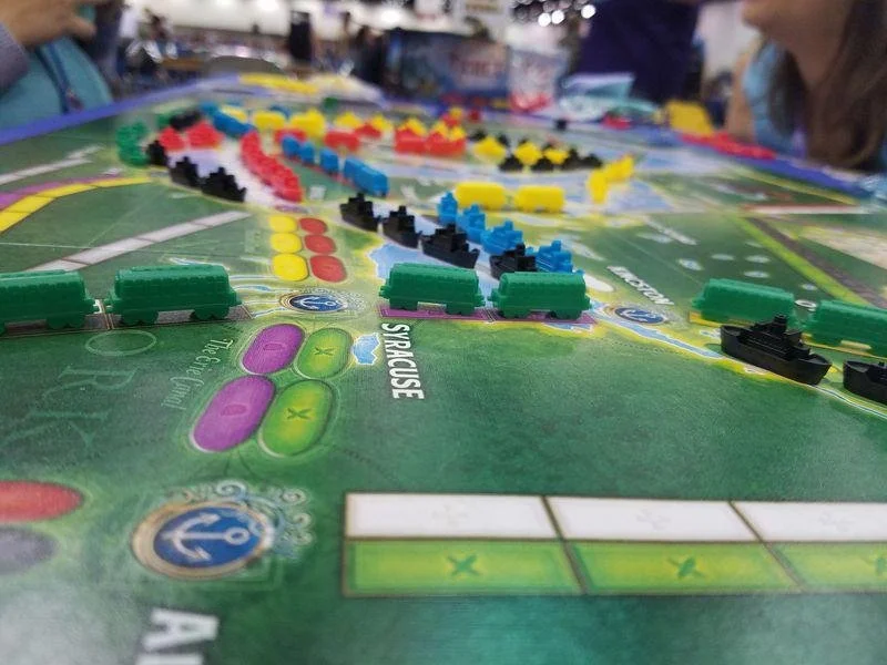 Close-up of a colorful board game with plastic patient pieces in a hospital-themed game environment, with players engaged in the game.