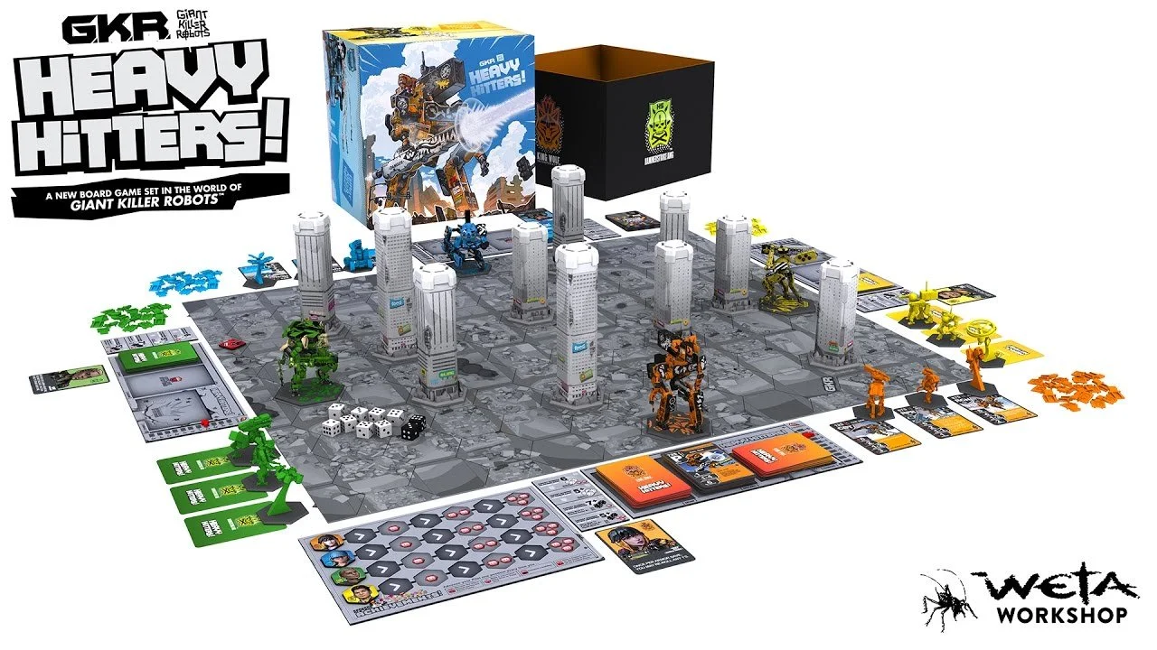 Board game setup called 'Heavy Hitters!' with miniatures and cards on a square game board, featuring tall building tiles and colorful game pieces.