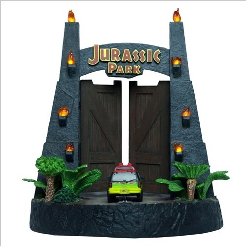 Jurassic Park themed archway with tall stone columns, flaming torch lights, wooden gates, the Jurassic Park logo, a small toy car, and plastic palm trees.
