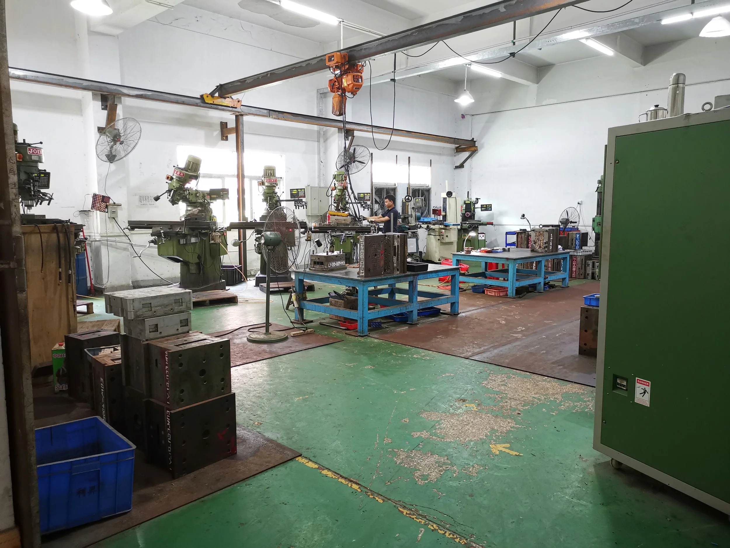 An industrial workshop with multiple metalworking machines, a worker operating equipment, and workbenches with tools.