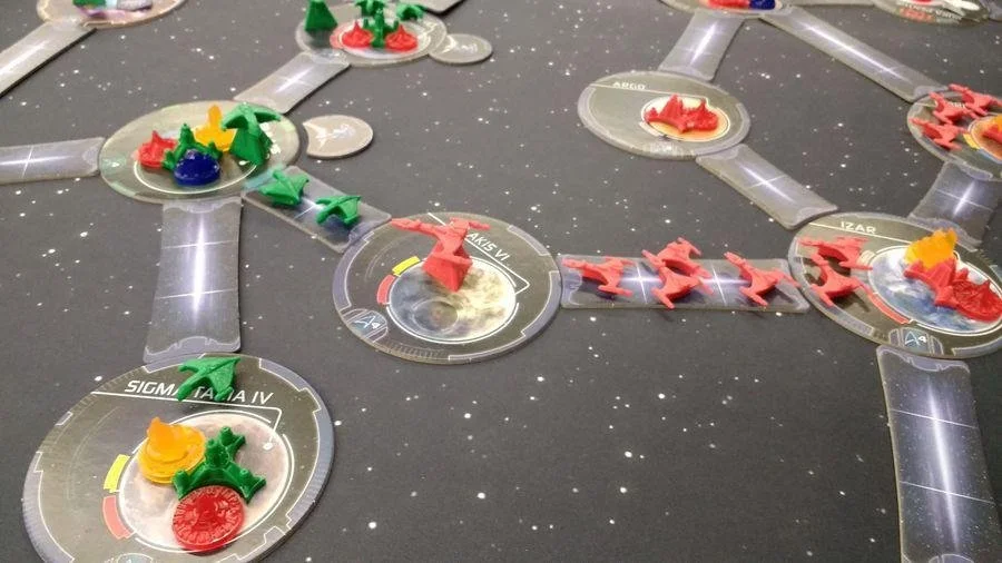 A board game set up on a star-themed surface with various colored plastic game pieces and circular game tokens.