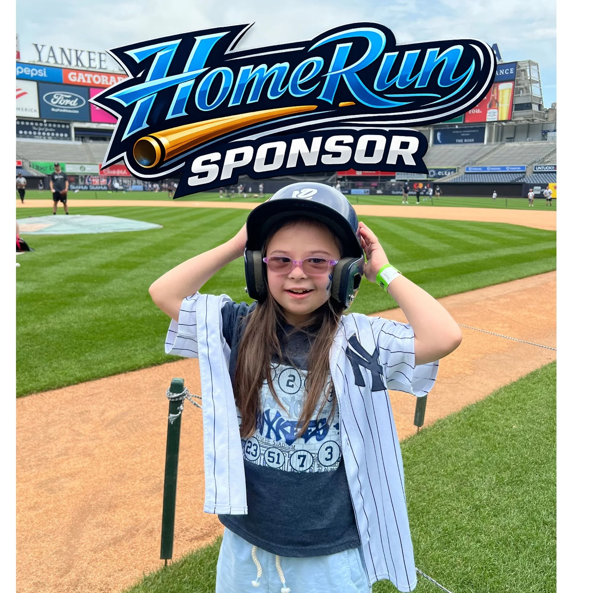 Young girl at a baseball stadium, wearing a New York Yankees jersey, helmet, and glasses, smiling and holding her helmet on her head, with the baseball field and stadium seating in the background.