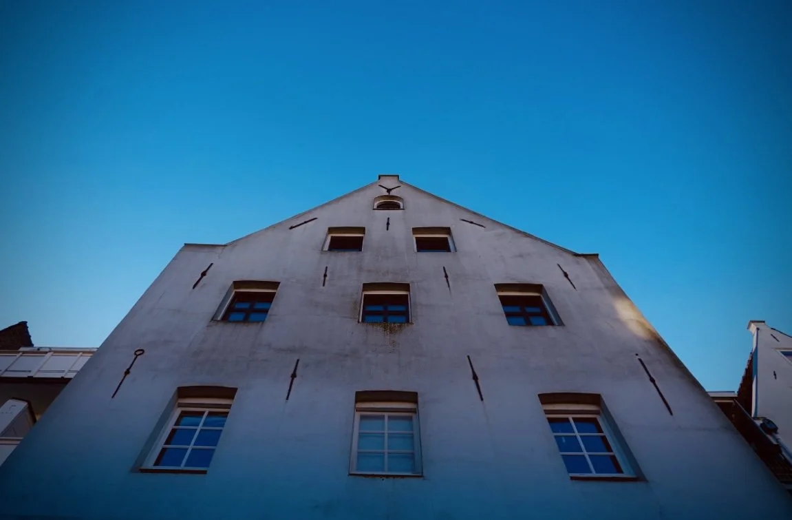 Low-angle view of a white building with multiple windows, set against a clear blue sky.