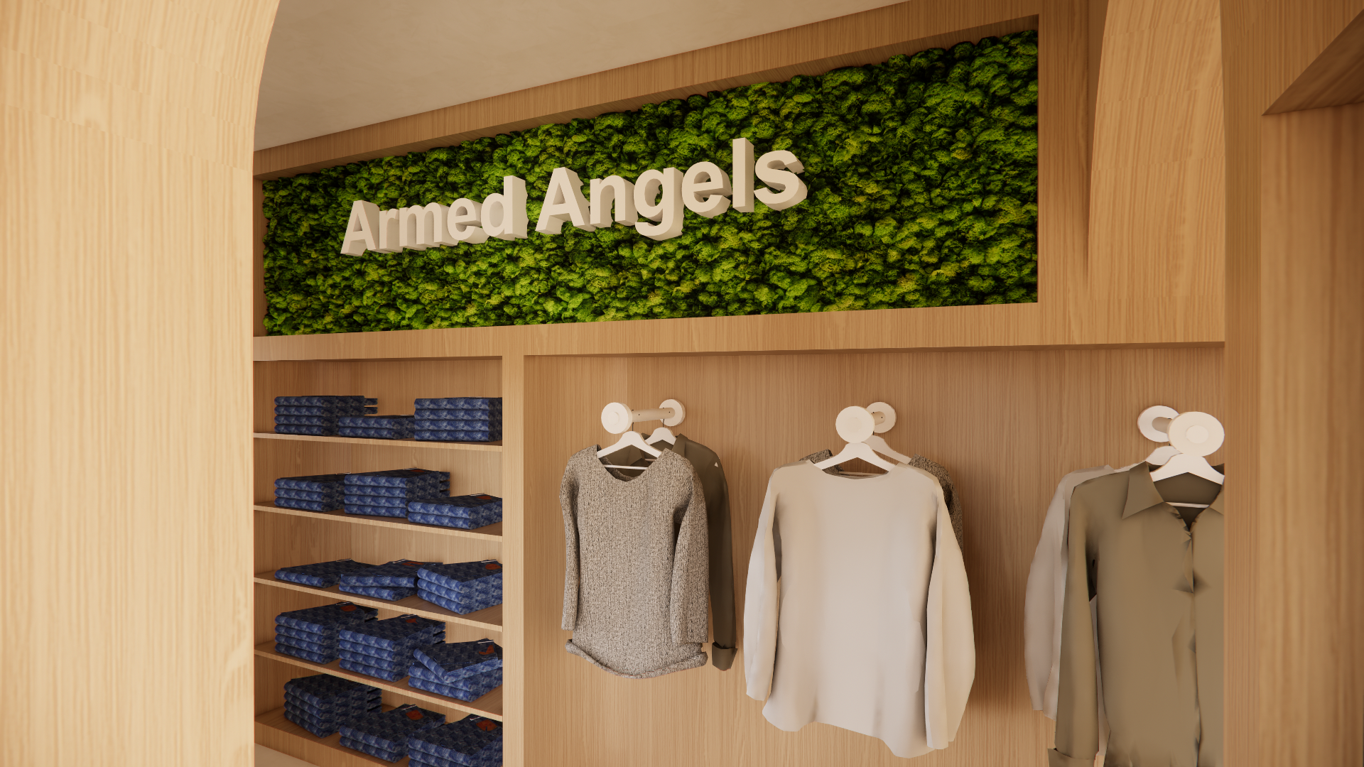 Clothing store display with stacked jackets on shelves and hanging shirts beneath a wall sign that reads 'Armed Angels' in white letters on a green moss background.