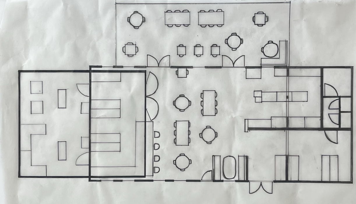 Floor plan of a building showing a conference or dining area with multiple tables and chairs, a separate room with seating, and a restroom area.